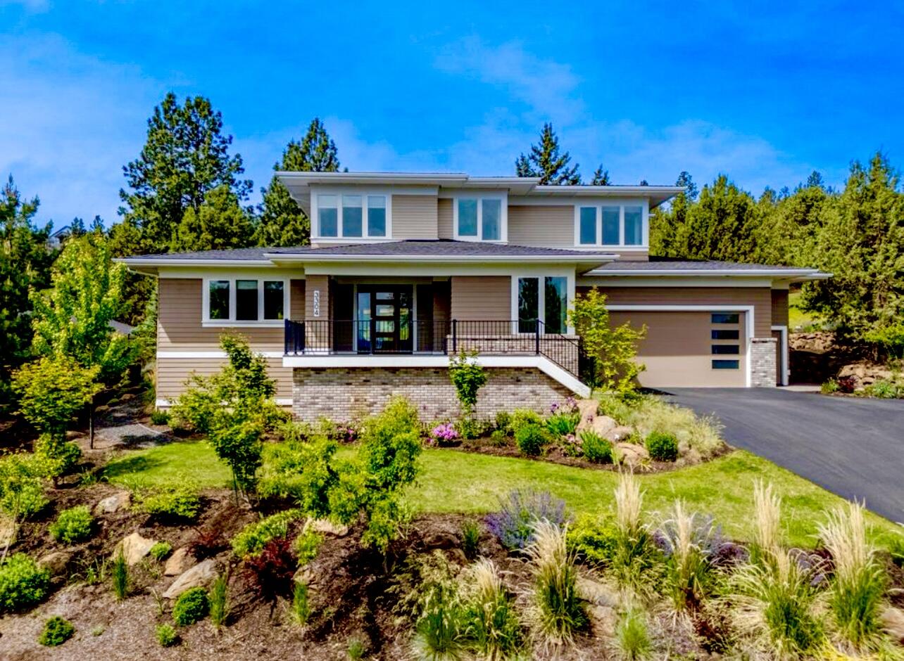 On Bend's NW side in River's Edge Village, this impressive Prairie Style home offers expansive views of the eastern skyline from an elevated homesite.  Built by award winning Structure Development NW, this expansive floor plan offers main level living with an open great room design featuring a fireplace w/ built-in cabinetry, large windows bringing in abundant natural light, spacious & well designed kitchen with quartz countertops, upgraded appliances & large center island. Wide plank wood floors, modern fixtures & lighting, & a gracious primary ensuite bedroom w/curbless shower, double vanities and walk-in closet. Office/den, laundry & mudroom also on main. Plus 3 bedrooms, full bath & bonus room upstairs. Enjoy outdoor living & entertaining with privacy on the covered back patio while viewing double golf course fairways & surrounding wooded, pastoral terrain.  Beautiful garden landscaping with perennial flower beds.  Large garage w/ enclosed hobby room.  Earth Advantage certified & Solar Panels.