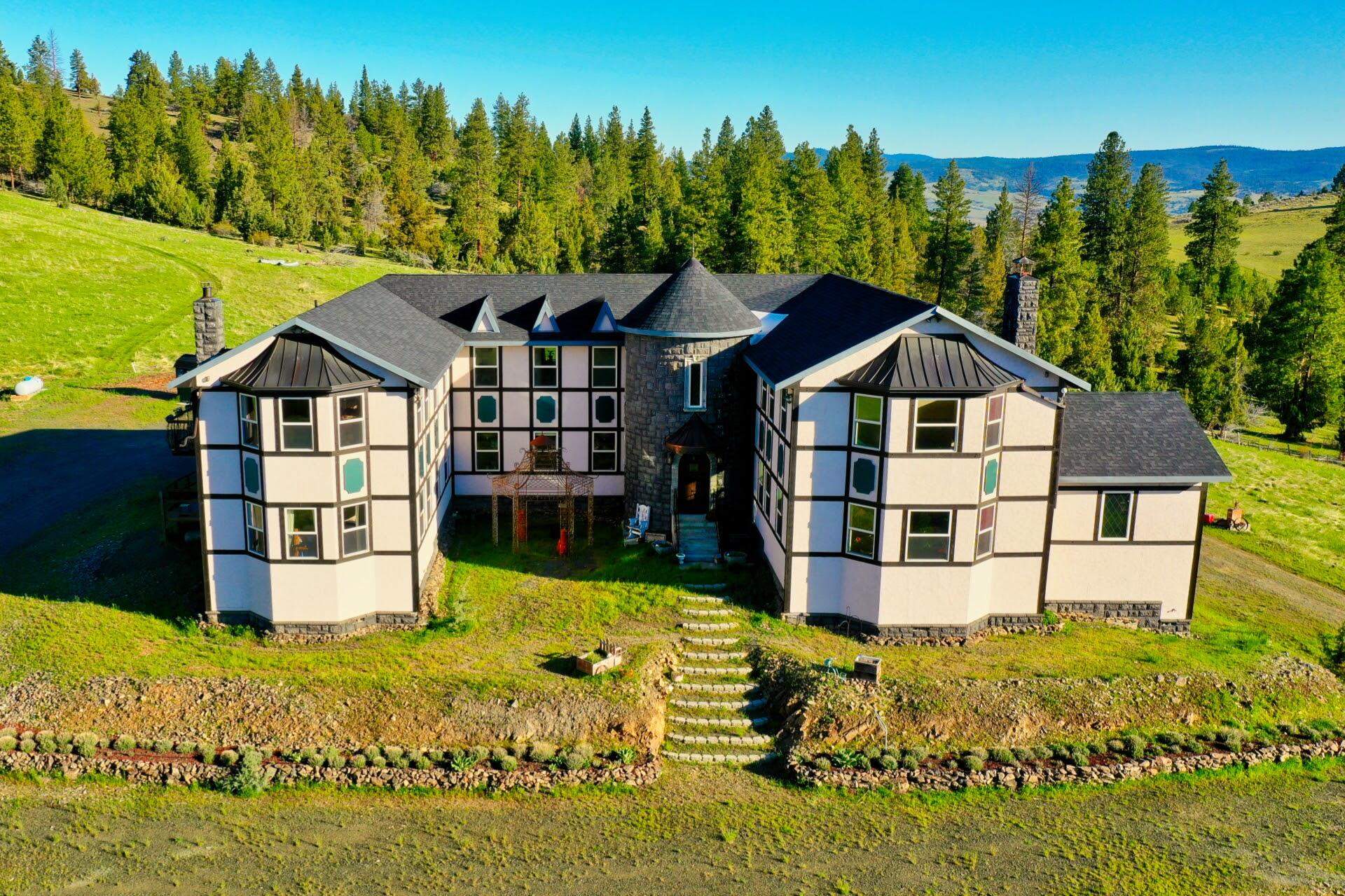 #250 A rare opportunity to own a property of this caliber- don't miss your chance to own this 7,164 sq ft home on 161.97+/- acres. The home features a spacious floor plan with upgrades throughout. 6 bedrooms, 4 ½ bathrooms with two of them being primary suites. The great room is inviting with high ceilings, fireplace and large windows allow natural light to flood the space. 990 sq ft garage with 3 electric garage doors and additional storage. It includes a sprinkler system, intercom system, and alarm system in the inner workings of this home. Hydronic wood furnace radiant floor heat.Approximately 15.78 acres of irrigation rights, pond, Pine Creek runs through lower portion, multiple fruit trees, pine and fir trees. Home is Spring fed with a 1,000-gallon cistern. Barn w/stalls, storage, lots of undercover storage for all your toys. This property is a must see to get the full experience of all it has to offer.For the investors this could make a great bed & breakfast, Air  BnB or retreat.