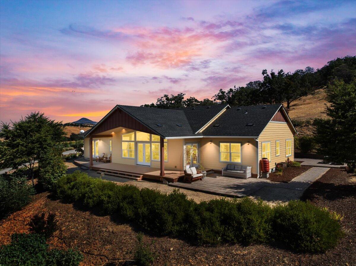 Panoramic mountain and valley views grace this light-filled single-level home minutes from East Medford, Talent, and Phoenix. Floor-to-ceiling windows in the vaulted great room capture magnificent sunset views. The open kitchen with granite counters, stainless appliances, breakfast bar, and walk-in pantry flows into the sunny great room, with access to two patios for easy indoor-outdoor living. Four bedrooms provide flexibility for family, guests, or home offices. The primary suite includes a patio with space for a hot tub. Light, neutral colors and cathedral ceilings create an airy feel; engineered wood flooring in living areas and bedrooms adds warmth and ease. A large laundry room with sink and storage, good well (recent flow test available), low-maintenance landscaping, greenhouse, and RV parking with power nearby make this home practical and inviting. New roof in 2025! Situated on 2+ acres in an upscale neighborhood, it's the perfect blend of privacy, space, and convenience.