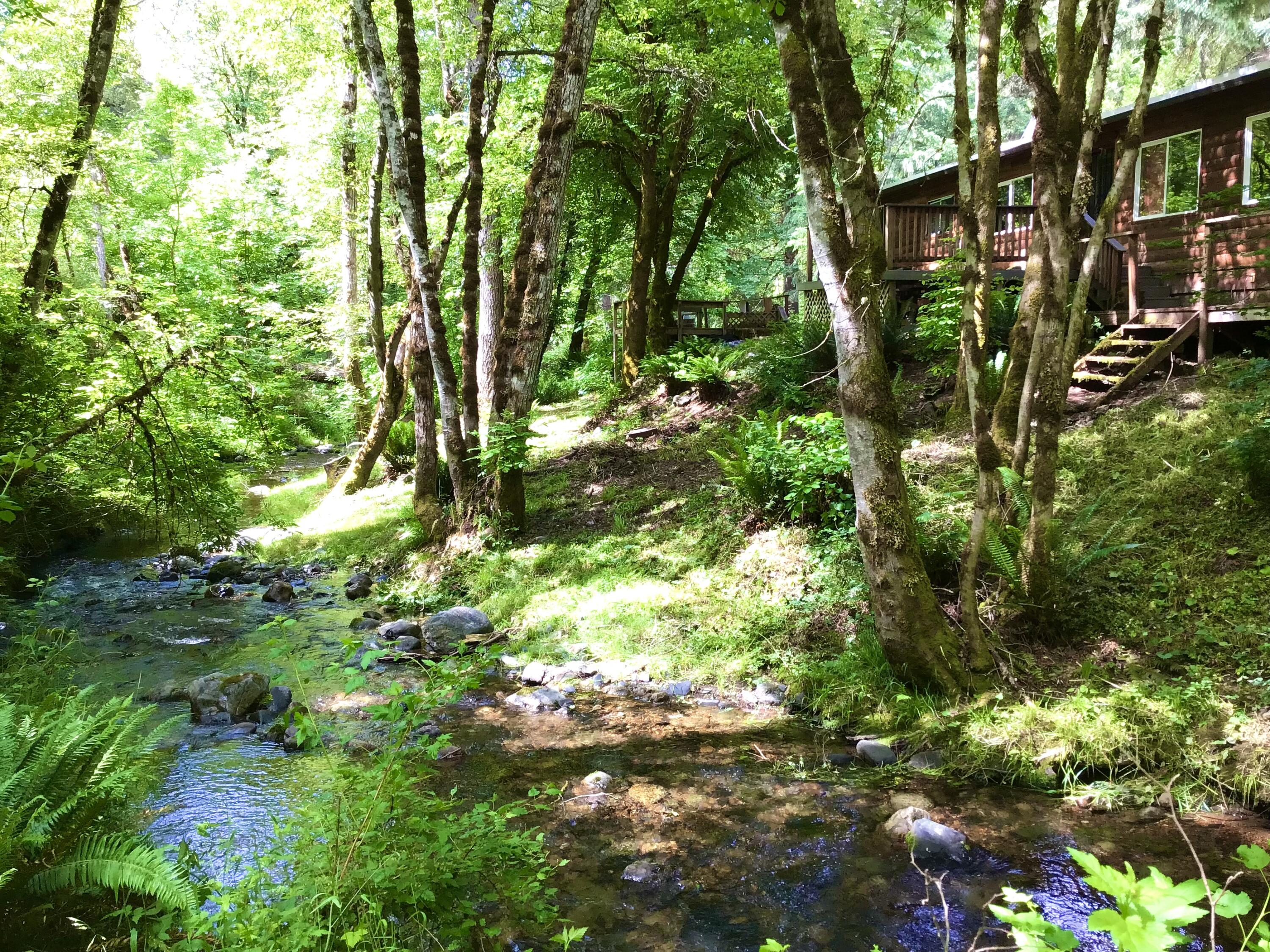 Creekside, off-grid cabin on 5 acres, perfect for customizing into your own private retreat or vacation home! This home is completely self-sufficient thanks to its solar setup, Pelton wheel hydroelectric system, and gravity-fed spring water for household use with water rights. Water source is 1,400 feet uphill with two, 2,500 gallon holding tanks. Inside, the property has been cleaned up and stripped down. You'll find two bedrooms and two full bathrooms, with a double vanity in the master. Lots of room to adapt the property to your needs between the spacious living and dining areas. The kitchen is fitted with a propane stove and refrigerator for your convenience. Moving outside, there is a 2-car covered carport, several outbuildings/storage including a shop area, and separate laundry area. Priced to sell quick, seller is motivated.