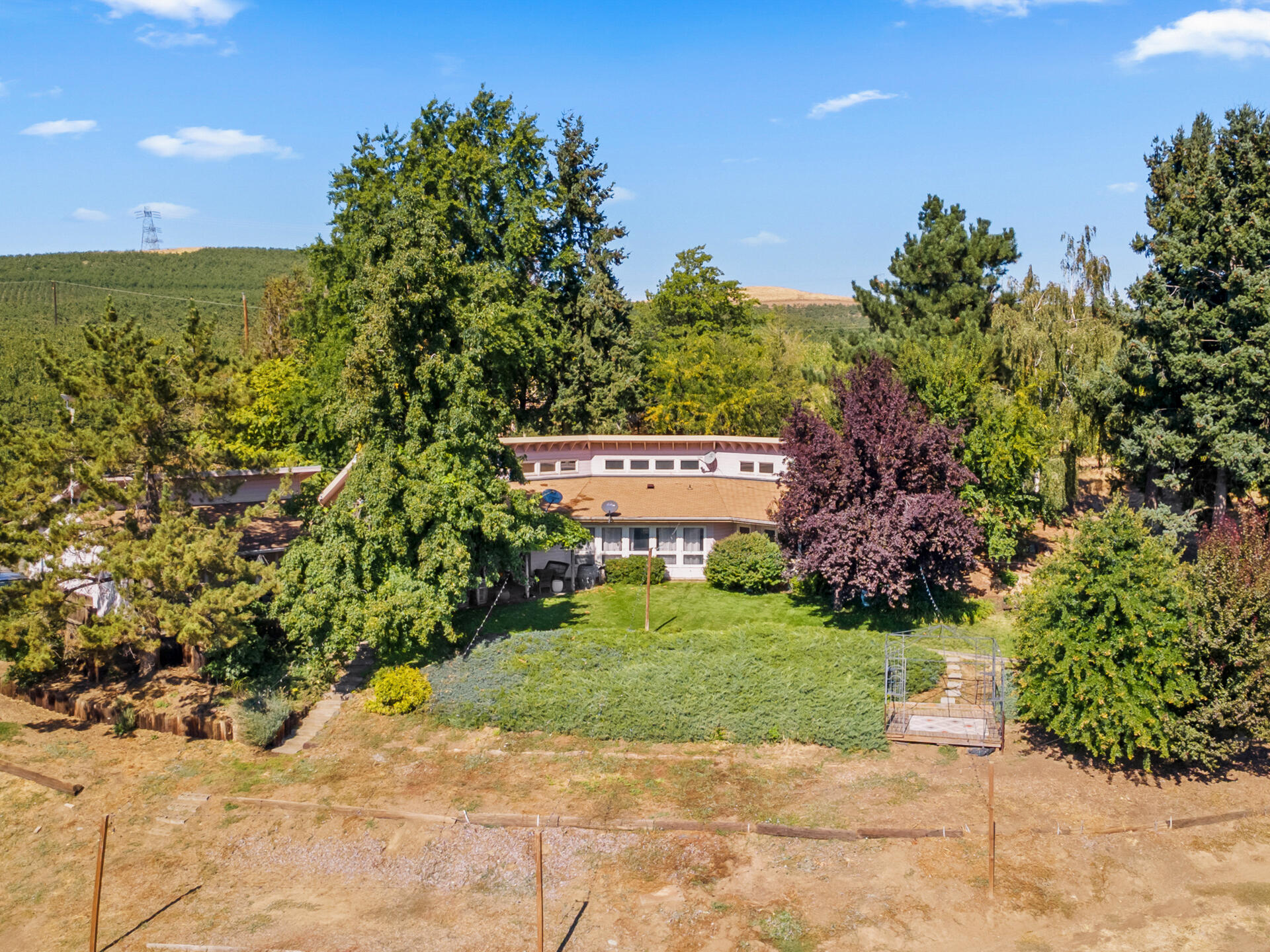 Nestled on just over 29 gently sloping acres, this stunning vineyard property offers the perfect blend of lifestyle, beauty, and agricultural opportunity. Planted between 1982 and 2001, the vineyard features premium varietals including Pinot Noir, Cabernet, Chardonnay, Riesling, and more — each thriving on the south-facing slope that maximizes sunlight exposure and grape quality. The vineyard is fully equipped with drip irrigation and frost mitigation sprinklers, with water provided by The Dalles Irrigation District, ensuring efficient and reliable management throughout the growing season. At the heart of the property sits a single-level, 2,000 sq. ft. home, built in 1983. This well-designed residence features three bedrooms and two bathrooms, a bright, open floor plan, and high ceilings that create an airy, inviting atmosphere. Large windows frame sweeping views of the surrounding vines, providing a serene backdrop from nearly every room.