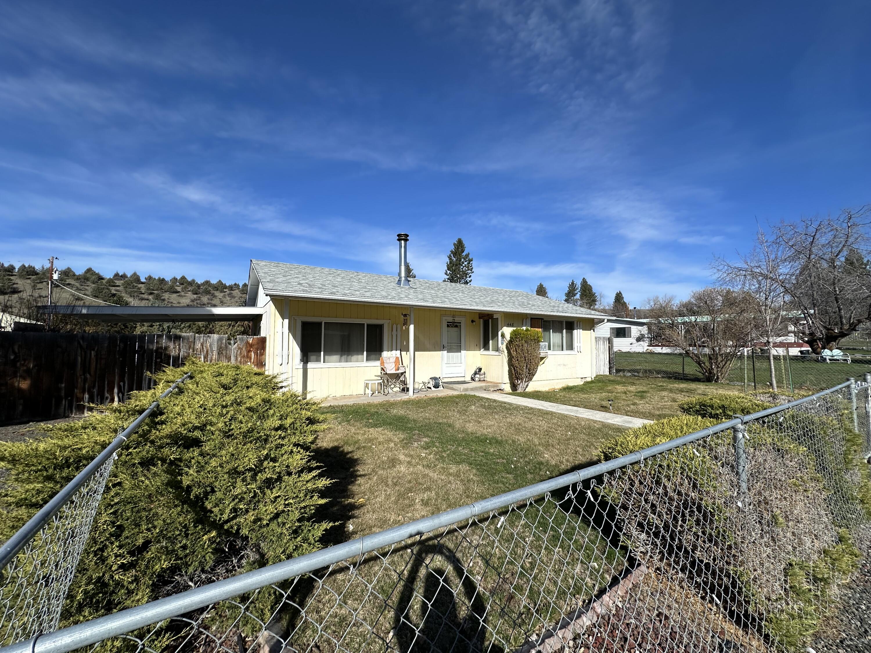 Charming 3-bedroom, 1-bath home offering 1,360 sq. ft. of living space on a 0.22-acre lot. The residence features a modern kitchen adorned with beautiful wooden cabinets and showcases attractive laminate flooring throughout the main living areas. Enjoy the spacious living room and family room, along with a large utility room that provides ample space for a freezer and an extra refrigerator. The expansive fenced yard includes a divider fence that separates the front from the back. Additional storage is available with two metal sheds and a wood shed. Access the alley from the back for easy firewood deliveries or parking for campers and toys. There is plenty of parking in front of the home as well. The heating options consist of a wood stove and an electric furnace. Step out through the sliding glass door to the covered patio for added privacy. This home was built in 1977 and has a tax amount of $1,548.05. MLS# 351324198 Office#399