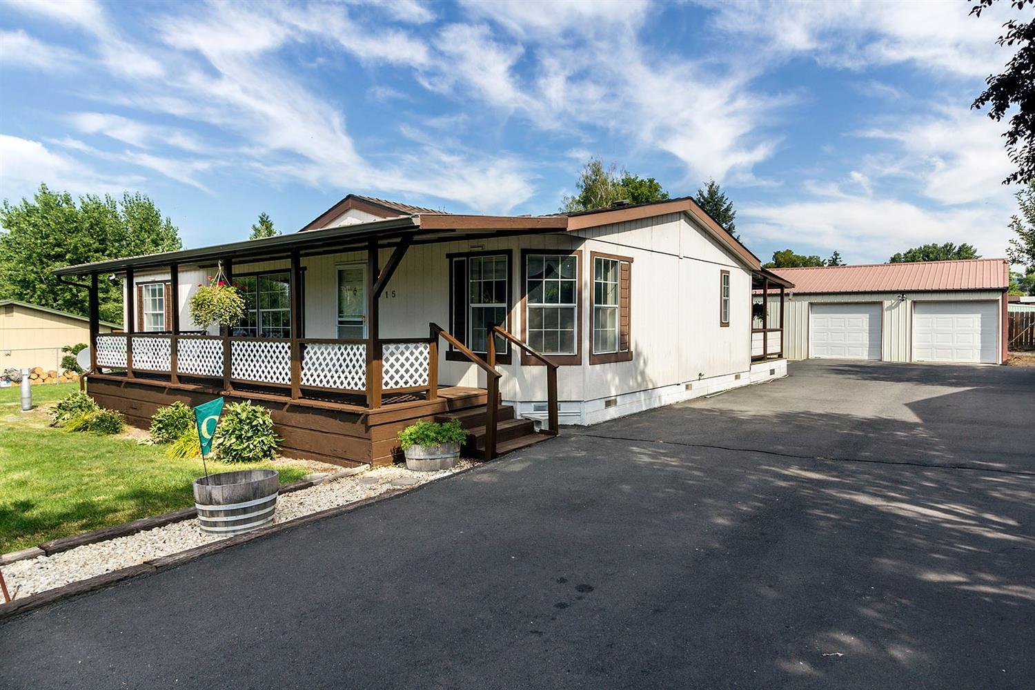 This 1992 air conditioned manufactured home sits on a fenced .34 acre on Mack Ave which is dead-end. The driveway has over 2,000 square feet paved parking and the driveway has a gate for privacy. The lot has sprinklers with city water there is a detached insulated garage 24 x 30 and has a work shop area inside with a 6 x 9 walk-in refrigeration cold storage unit. There is a sewer connection for RV. The home has a 9 x 17 front covered porch and a 9 x 14 room addition off the dining area and kitchen plus a separate covered porch. The laundry room has additional custom cabinets. Owner reports the roof is only 8 years old since replaced. This home also has a 20 x 13 concrete patio; storage shed on concrete pad and raised planters for a garden. All appliances are staying including the refrigerator and washer and dryer.
