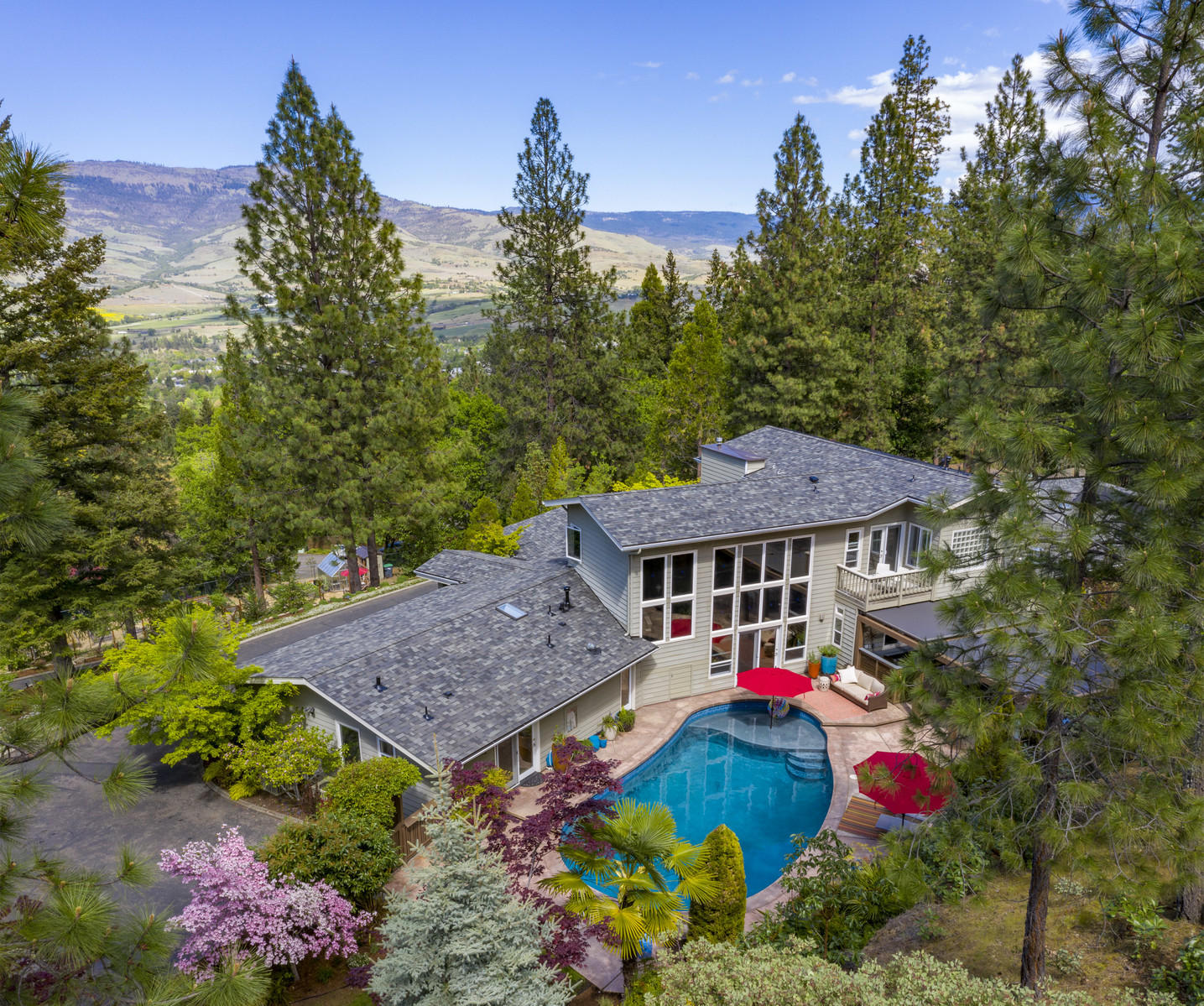 This singular home offers seclusion and serenity within easy reach of downtown. Contemporary design with flowing floorplan is light-filled and surrounded by park-like acreage suited for full-scale entertaining, quiet retreat, work-from-home, cultivator's delight, or all-day relaxation. Expansive valley views from living areas are complemented by the privacy of the pool, spa, outdoor kitchen, fire pit and quiet gardens opening into backyard. The well-appointed chef's kitchen is the heartbeat of open living, dining and family rooms. Laundry, powder bath, storage and exercise/office areas are adjacent. The west wing invites calm with 3 bedrooms/2 baths that converts to guest quarters with separate entrance. Upstairs master presents luxe comfort. Large bedroom with space to lounge, 2 bathrooms and separate glass-walled euro-spa tub. Gated circular drive winds through lower gardens with private vineyard, vegetable garden, fruit trees and greenhouse to arrive at this comforting sanctuary.