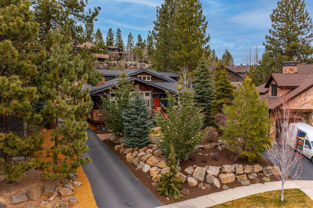 Streaming through a wall of south facing windows, natural light floods the great room of this Shelvin Ridge home, highlighting wood lined vaulted ceilings, floor to ceiling stone fireplace and a center island kitchen with plentiful storage & 6 burner gas range. Perfectly sited back off the street & screened by many mature trees, this home enjoys an enhanced sense of privacy, taking full advantage of the large .39 acre lot. The main level includes a light-filled private office just off the entry & a primary suite anchored by a large bath with dual vanity, jetted tub & full tile & stone shower. Upstairs, 2 bedrooms, 2 full baths & a vaulted bonus room with extensive storage and multiple skylights. Enjoy year round outdoor living on the large covered deck with access to a beautifully landscaped, fully fenced backyard with stunning, year round waterfall & large paver patio. With a wrap around deck & enclosed under deck gear storage, this is the perfect base camp for your Bend adventures!