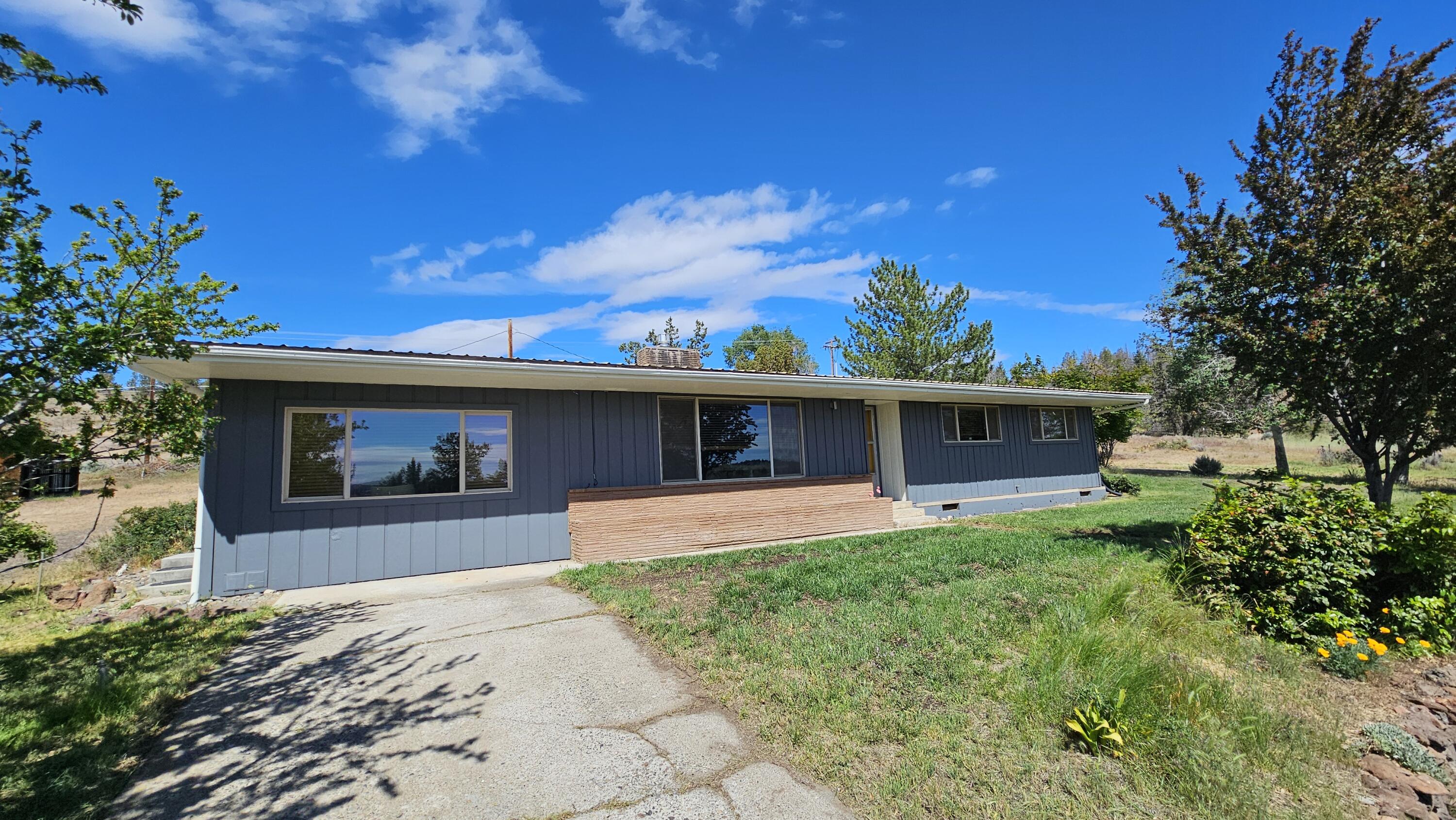 Seller now offering HOME WARRANTY ! 
Come see this Mid Century Modern home in the country overlooking the city of Madras. This rare gem has been tastefully updated with out changing the feel of the mid century modern home that is so desired today ! Original hardwood floors as you enter the home, with stunning original brick surrounding an updated gas insert fireplace.  The open floor plan also offers both a living and an oversized family room and office space area which overlooks the town. The sunrise views of the valley, city, and natural terrain brings the perfect spot for morning coffee with a peaceful setting while sitting on just over one acre.  This home offers 3 bedrooms and 2 bathroom, the primary suite bathroom with a stunning modern update !  Outside there is an RV garage with storage and a perfect work spot area. The desirable location is just above town close to all desired needs in town.