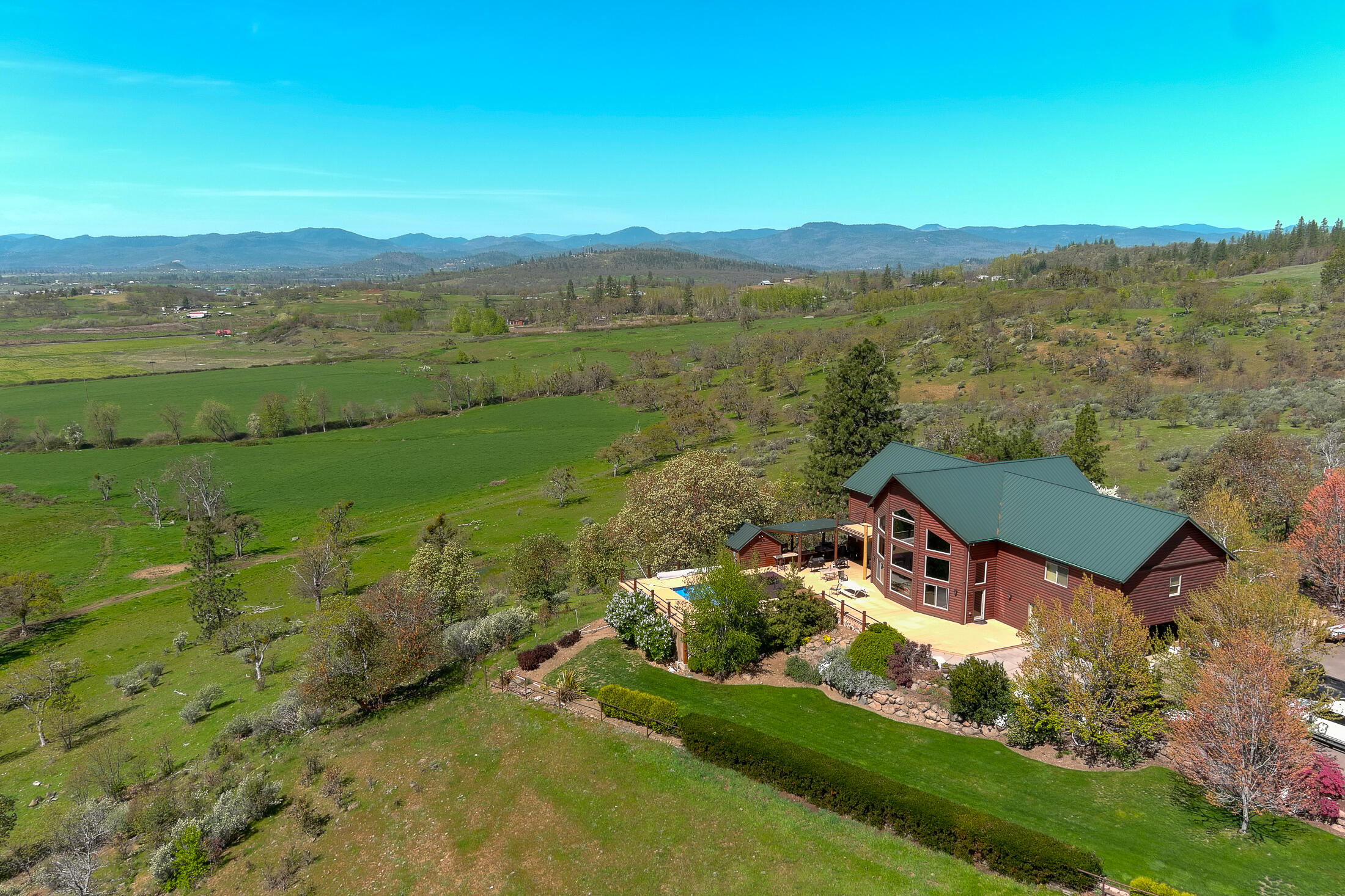This premier Southern Oregon ranch offers 586+ acres of beauty, productivity, and premier ranching infrastructure in Southern Oregon. 351 acres of abundant water rights, fertile soils, and laser-leveled hay fields produce 360-400 tons of grass hay annually, while supporting 160 cow-calf pairs and 80 developing bulls. Covered pipe-fenced corrals feature multiple pens, fresh water, hydraulic chute, and livestock scales. Facilities include two 500-ton hay barns, calving barn, show barn with 6 runs and wash rack, bull lots with concrete pads and bunks, and multiple livestock barns. The 3,965 sq. ft. custom home offers 4 bedrooms, 3.5 baths, hand-scraped hardwood floors, granite counters, commercial-grade appliances, and sweeping Rogue Valley views. Additional dwellings include a ranch-manager home and duplex for staff or guests. Medford City water services the residences and select barns. A rare opportunity to own a productive ranch with exceptional amenities in a stunning setting.