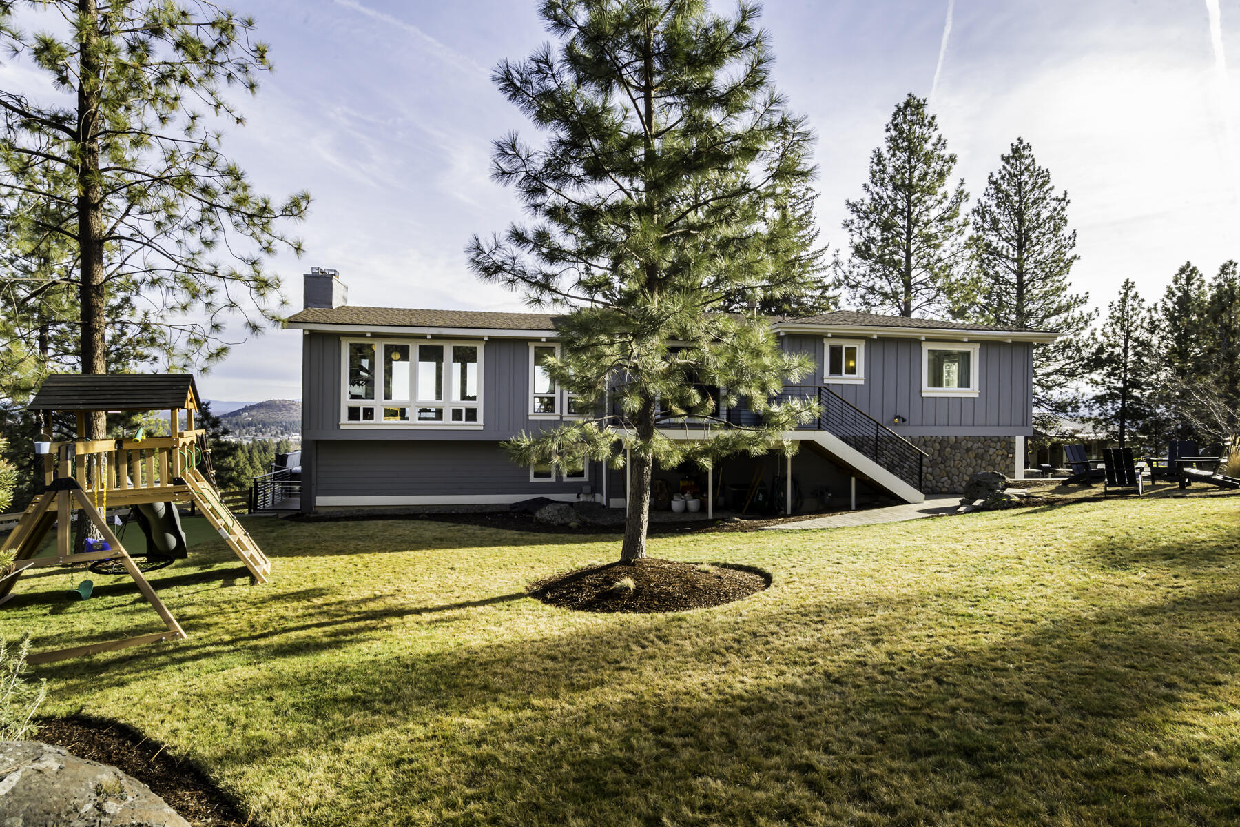 Located in the desirable neighborhood of West Hills sits this stunningly renovated home with unobstructed easterly and city views!  Over 2000 square feet of new trex decking, a newly landscaped yard, and a personal two-hole putting green make this the perfect place to entertain and enjoy Bend's beautiful outdoors. The open floorplan upstairs allows for an abundance of natural light with floor-to-ceiling windows in the kitchen, dining, and living areas.  A newly updated Primary Bedroom and Bath playfully combines earthy tones and modern fixtures...a beautiful space to relax and unwind. Downstairs there is an additional family room, fireplace, 2 additional bedrooms, one full bath, and a mud room/laundry room. The spacious 2-car garage has plenty of space for all your Central Oregon Toys.  You will not want to miss this rare opportunity to own a completely renovated West Hills home with an abundance of outdoor space and spectacular views!