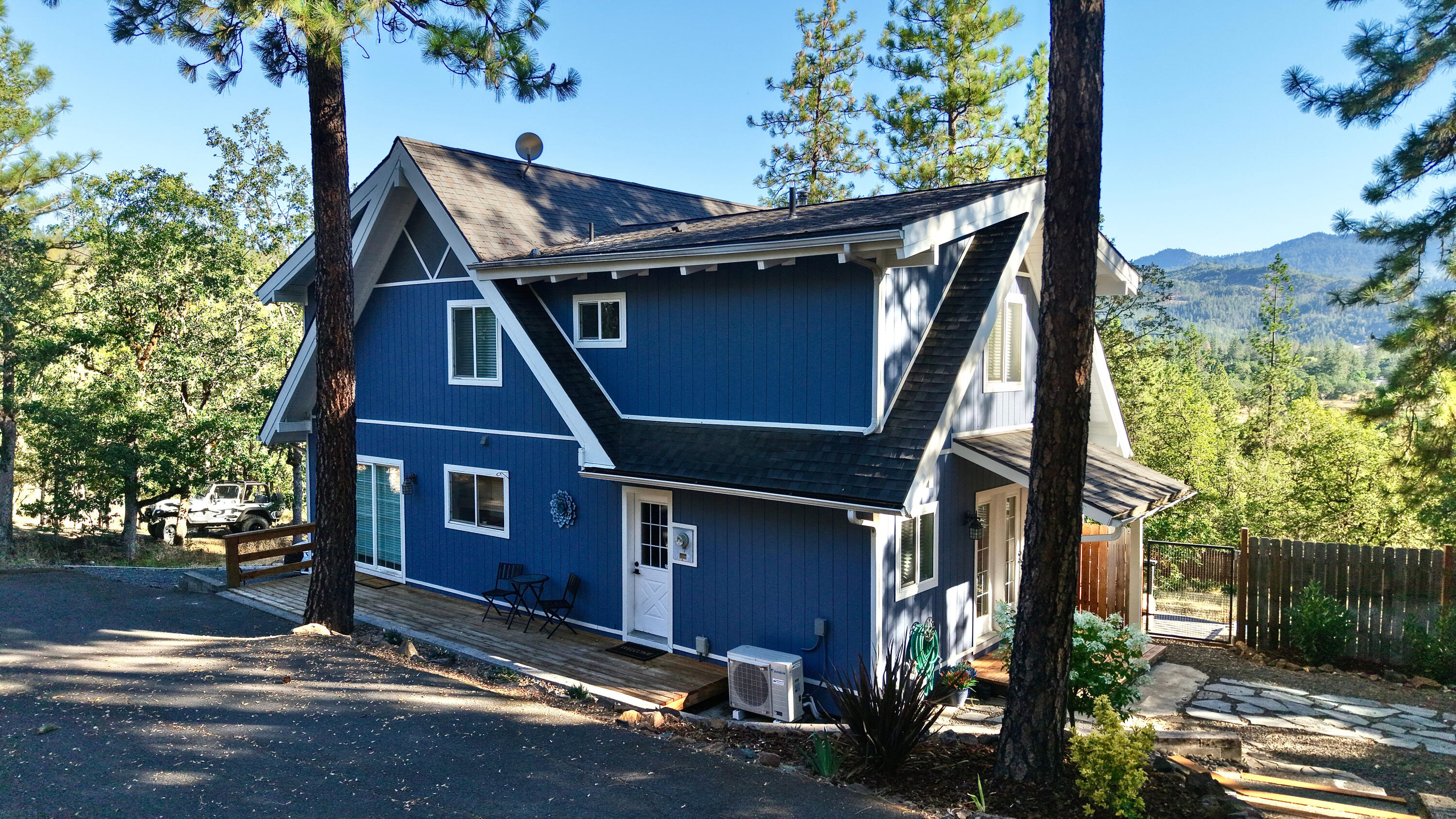 End-of-the-Road Privacy. Sweeping views of the surrounding mountains and forest await you in this stunning home, tucked away in one of Shady Cove's premier neighborhoods. Set on a spacious half-acre, this nearly 1,800-sq. ft. home offers the peace and privacy of a rural setting. Inside, the warm and rustic kitchen features wood cabinetry, updated appliances, a pantry, and charming details throughout. Vaulted ceilings and expansive windows frame dramatic natural vistas, while an open loft staircase leads to a bonus area and a private primary suite with attached bath and additional bedroom. Downstairs, you'll find a convenient laundry room, a second full bath, and a versatile oversized bedroom—perfect as a guest room, home office, family room, or craft room. The outdoor space invites you to relax or entertain with a cozy firepit area and a large, fully fenced yard ready for your personal touch. Come experience the perfect blend of seclusion, style, and convenience!
