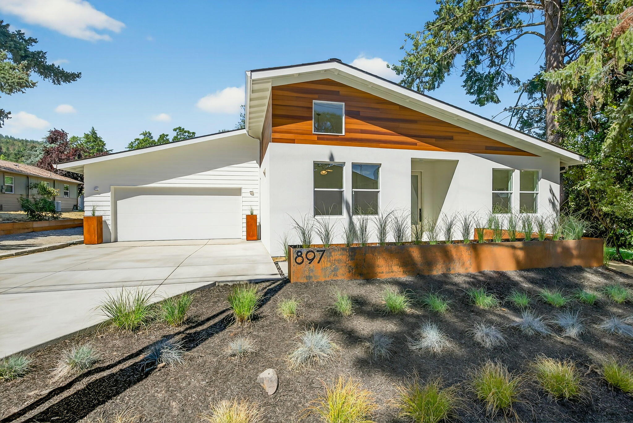 Architecturally inspired new construction with midcentury vibes on a hard to find level .18 acre lot. This custom 3 bed, 2 bath home with office wraps around a window-filled atrium that floods the living spaces with light. The kitchen offers a large island with eating bar and opens to a bright great room with tall ceilings, custom built window package, and fireplace with brick surround. The primary suite bath features floor to ceiling tile, a roll-in shower, and floating double vanity. Built by Suncrest Homes, a trusted Ashland builder with over 35 years of experience, this Earth Advantage home delivers energy efficiency, healthier air, and exceeds standard building code. Exterior details include clean elevations with clear vertical grain cedar and stucco, tailor-made steel planters that frame the entry, covered porches, an outdoor gas fire pit, and drip irrigated raised beds with potting station. Set among mature trees with fresh landscaping, this home balances design and lifestyle