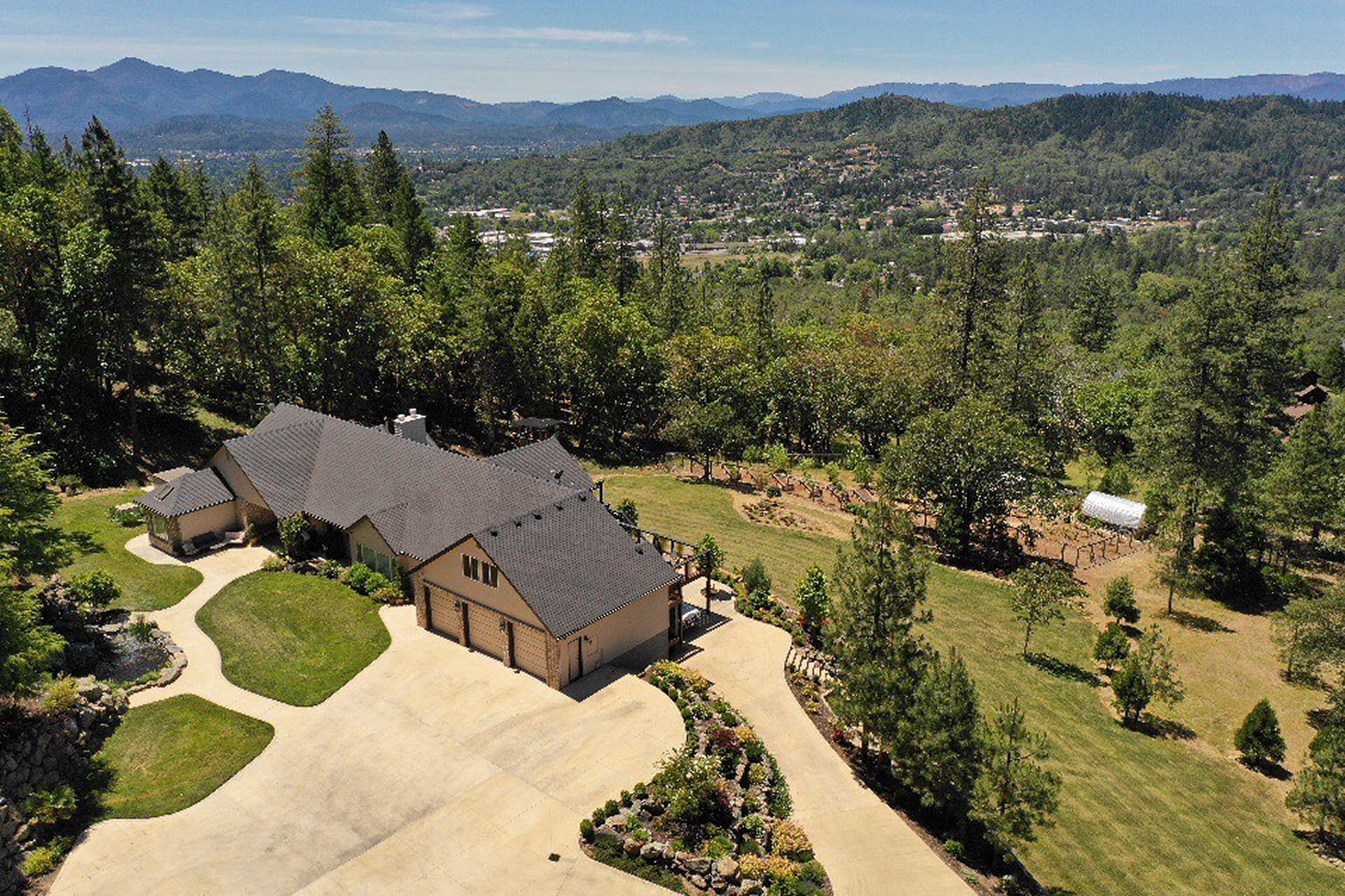 Price Reduced & Move-in Ready! 4 Bed +Office +Bonus Room on 5 acres backed by BLM. Convenient to I-5 & Downtown Grants Pass. Oversized Primary Suite on main floor has private deck, jacuzzi tub, walk-in closet & more. Kitchen is designed for the home chef with butcher block island, stainless steel appliances including a Viking 48'' duel-fuel range w/ commercial hood, warming drawer, custom cabinets, granite, & more. Great Room, Office, Sunroom & Laundry/Mudroom on main floor. Bonus Room above 3-car Garage. Beautiful custom hardwood floors recently professionally refinished. Downstairs you'll find a Kitchenette/Bar, Living Room w/ patio access, & 3 Bedrooms with their own Bathrooms. Outside, the established landscaping is complimented by a Large Koi Pond tucked into the impressive rock wall. Ample Concrete Parking with Basketball Hoop, Carport/Boatshed, fenced Garden with fruit trees, grape vines, raised beds & greenhouse. 30 GPM well. Dist7 schools. 
Gated asphalt drivew