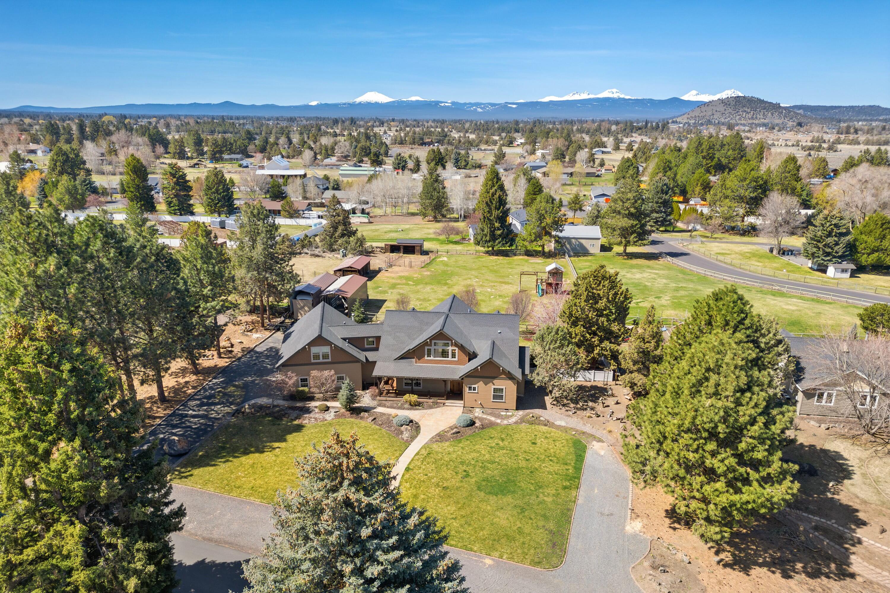 Welcome to 61939 Dobbin Rd, located in desirable Dobbin Acres, where country charm meets modern convenience. Just minutes from town, this private retreat offers a peaceful lifestyle with room to roam. The beautifully landscaped, irrigated and fully fenced property is perfect for entertaining. Horse lovers will appreciate the small barn with two stalls, while hobbyists will love the multiple garages, workshop, and covered RV parking. Inside this gorgeous custom home, you will find reclaimed wood floors and a stunning kitchen w/concrete counters and copper accents. The living room boasts large picture windows and a cozy fireplace creating a warm, inviting atmosphere. The spacious primary suite features a spa-like bath, plus an additional office/guest room on the main level with a full bath. Upstairs, you'll find two more bedrooms, a bath, a large bonus room, and a workout room. Don't miss this rare opportunity for country living just minutes from shopping, schools, and medical services!