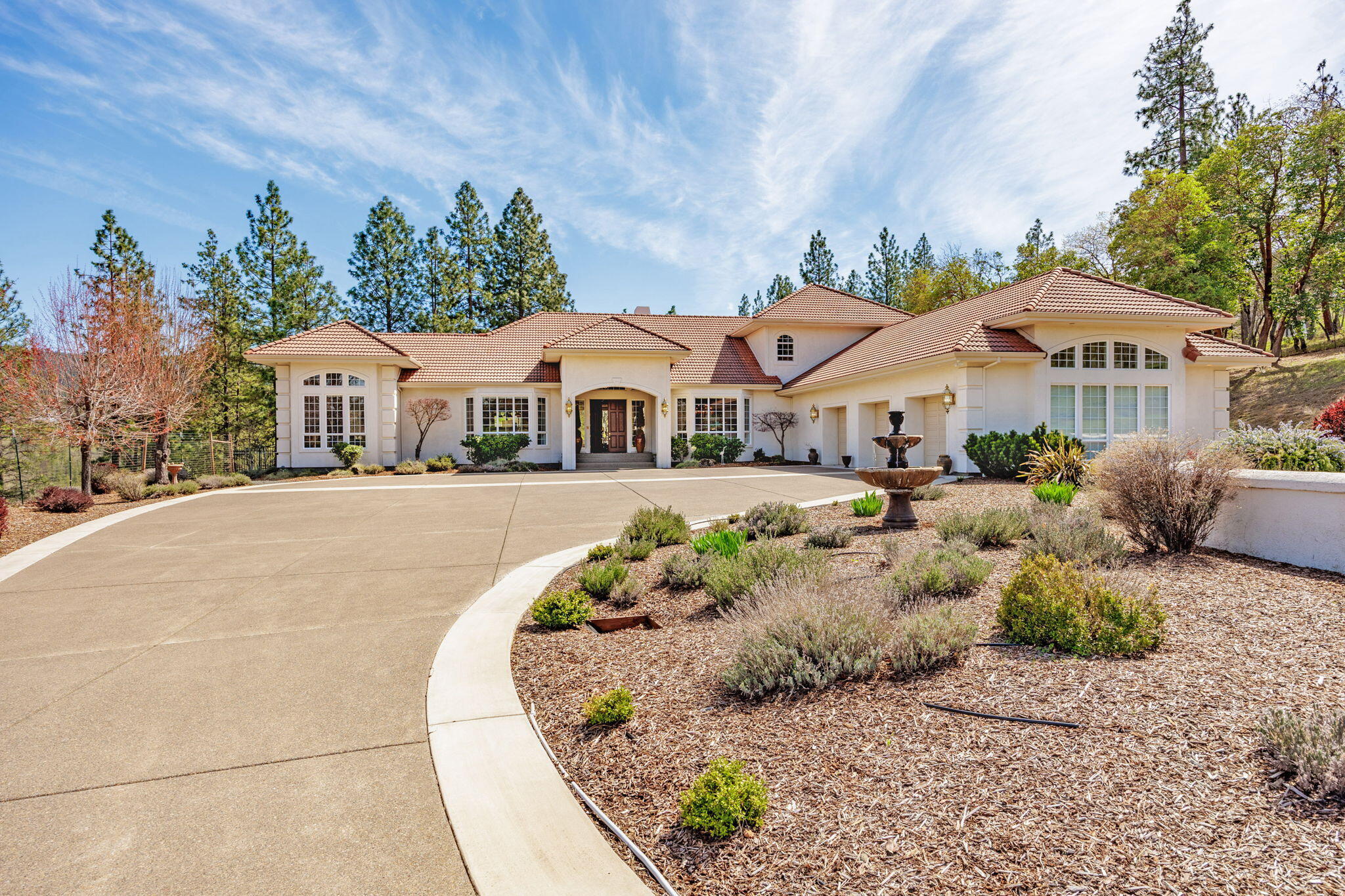 Stunning Mediterranean estate in the sought-after Sun Ridge Estates—a luxurious, close-in rural community surrounded by equally elegant estate properties. Custom-built 5,776 sq ft home features true main-level living. 4 beds, 5.5 baths on 4.84 acres, perched high overlooking park-like grounds and mountain views. Open and inviting floorplan with incredible natural light. Spacious and well-appointed kitchen makes indoor entertaining a breeze. It has ample storage, great counterspace and convenient access to the outdoor patio and pool. Formal and informal living as well as dining. Primary suites on each level. Main level suite features a spa-like bathroom, jetted tub, tile shower & an adjacent sitting room for quiet mornings away from the hustle and bustle. There is second suite upstairs with a private patio. Custom in-ground pool, tiled cabana with full bathroom. Gated drive, beautiful entry and plenty of parking both inside the 1400 + SF garage/shop and on the property.