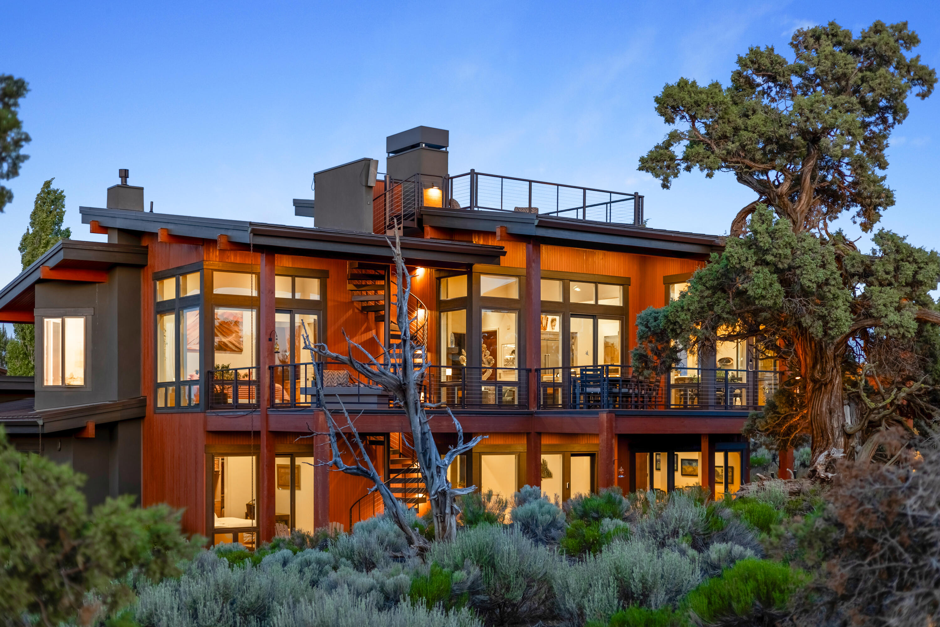 A breathtaking, award-winning home in Juniper Preserve - The Club at Pronghorn. This 3,579 SF high-desert retreat overlooks the 4th green & 5th tee of the Tom Fazio Championship Course with stunning panoramic views from Mt. Bachelor to Mt. Hood. Bordered by protected BLM land, views remain forever unspoiled. A reverse-living design offers a private elevator, floating staircase, rooftop patio with 360° vistas, and outdoor spiral stairs. The upper level features a chef's kitchen with Wolf appliances, Sub-Zero fridge/freezer, walk-in pantry, great room with linear fireplace, and a primary suite with copper soaking tub, heated floors, and massive closet with laundry. 2 downstairs bedrooms and an en-suite with kitchenette & private entry, cozy den, workout room with golf simulator, and smart home AV closet. Three-car garage with workshop, four outdoor living areas, and direct course access complete this rare find.