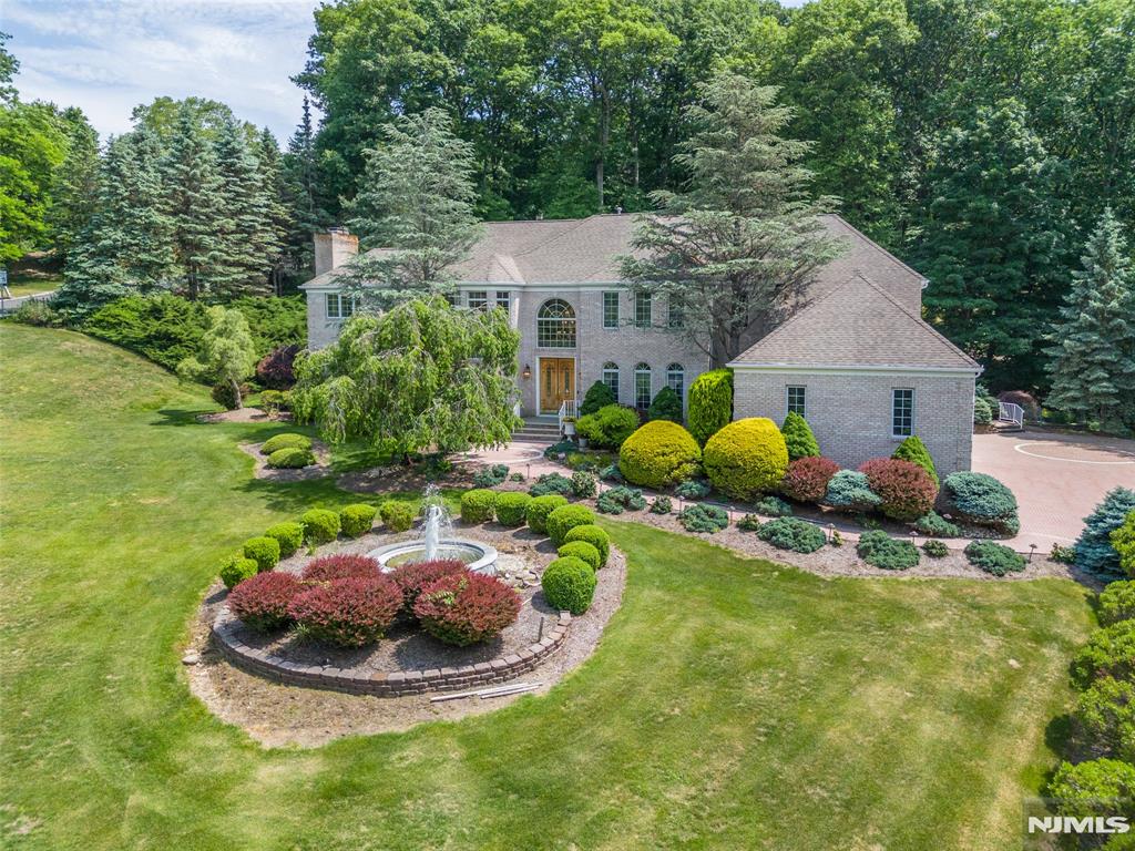 Nestled on a nearly 2 acre corner lot in Kinnelon's sought-after Raine Tree neighborhood, this magnificent brick-front Colonial offers exceptional luxury, space, and versatility on a quiet cul-de-sac. Impressive curb appeal sets the stage with manicured landscaping, a sweeping paver driveway, and a stately circular fountain. Inside, the grand 2 story foyer features polished marble flooring and a sweeping staircase. Elegant formal living room, relaxation room with fireplace and dining rooms provide the perfect setting for entertaining, while a private office offers an ideal work-from-home space.The soaring great room with gas fireplace flows into the chefs kitchen, complete with an oversized center island, breakfast bar, and walk-in pantry. A first-floor guest suite with a full bath and a laundry room adds convenience for extended living arrangements.Upstairs, the primary suite features a tray ceiling, walk-in closet, and spa-inspired bath with a jetted tub. Four additional bedrooms and two additional full baths complete this level. The fully finished lower level offers incredible bonus space or extended living arrangements. Designed for entertainment, it features a massive media room with a projection theater screen, a recreation room, den, office, powder room, and a fully equipped second kitchen.Equipped with multi-zone HVAC, a whole-house generator hookup, and a 3 car garage, this extraordinary estate on a park-like property combines timeless elegance with modern amenities.