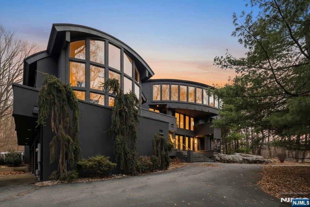 Welcome to this striking, fully-renovated modern masterpiece set on over 3 private acres in the prestigious, gated Smoke Rise community. One-of-a-kind contemporary residence delivers 6,000+ sq ft of architectural luxury. Designed to impress from every angle, the home blends bold modern lines with warm materials, creating an atmosphere that feels both sophisticated & effortlessly alluring. The dramatic entry opens to a soaring two-story living area, wrapped in glass and anchored by architectural sight-lines that flood the home with natural light. The expansive great room features a stunning wall of windows & a sculptural barrel ceilingâ€”an entertainerâ€™s dream space that feels as breathtaking at dusk as it does at dawn. The entire second level is a private primary sanctuary, a full-floor retreat floating above the main living spaces. A gallery corridor overlooks the dramatic rooms below and leads to a sumptuous primary suite complete with a spacious spa bath, custom closet, intimate sitting area, & a series of private balconies and terraces that surround the homeâ€”offering serene views in every direction. A bonus walk-up attic was conveniently converted to the perfect guest suite. The main level also provides incredible flexibility with 3 bedrooms, 2 full baths, generous storage, & sleek 3-car garage. Set within one of New Jerseyâ€™s most coveted private lake communities, this modern showpiece offers rare design, unparalleled privacy,& an ambiance that is truly unforgettabl