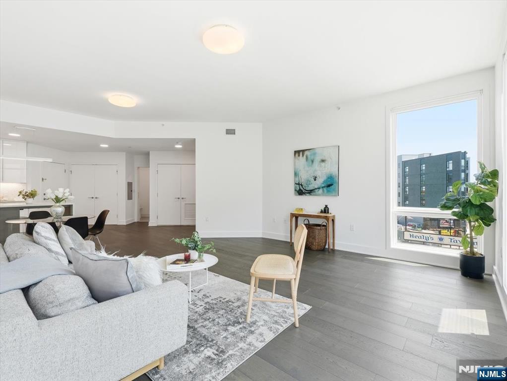 An exceptional residence, with deeded garage parking, in the heart of it all. Impeccably crafted, this stunning two-bedroom, two-bathroom condominium represents the pinnacle of refined urban living. Every inch of the generous layout has been designed with the most discerning buyer in mind, from wide-plank 8" white oak floors to soaring high ceilings throughout. The chef's kitchen dazzles with sleek modern cabinetry, professional-grade Jenn-Air appliances, a vented range hood, porcelain mosaic backsplash, and a dramatic Carrara Grigio waterfall-edge island. The spa-inspired primary bath features a floating wall-hung vanity, rain shower, and European porcelain tile throughout. Large Pella designer casement windows flood every room with natural light, while a walk-in closet, central air and heat, and a deeded garage parking space round out this turnkey offering. Outside, a breathtaking green roof terrace, complete with BBQ areas and an outdoor screening room, sets the stage for effortless entertaining against sweeping New York City skyline views. Building amenities include a state-of-the-art fitness center, children's playroom, secured package room, bike storage, and virtual doorman. Steps from PATH trains, parks, acclaimed dining, and vibrant nightlife.