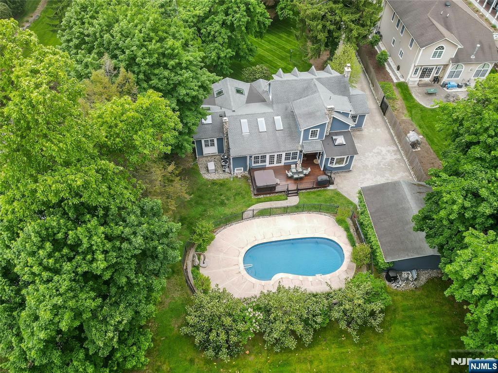 This exceptional home is set on a beautifully landscaped over one acre of park-like property. Surrounded by lush greenery and mature plantings, the setting offers complete privacy and a true resort-style atmosphere. A charming mahogany front porch with classic Hampton-style appeal welcomes you to the home. The home features a desirable first-floor primary suite with skylights, offering privacy, convenience, and serene views of the grounds. The great room features cathedral ceilings and skylights overlooking the beautiful backyard setting. The second floor includes three additional bedrooms and a fully renovated family bath. Outdoor living is equally impressive, highlighted by a fiberglass heated salt water pool with Sundance Spa (Hot-Tub) and an expansive tropical hardwood Ipe deck, perfect for entertaining, dining, or relaxing in the tranquil backyard oasis. In addition to the detached two-car garage, the property offers driveway parking for up to five additional vehicles - a rare offering that must be experienced in person to truly appreciate all it has to offer.
