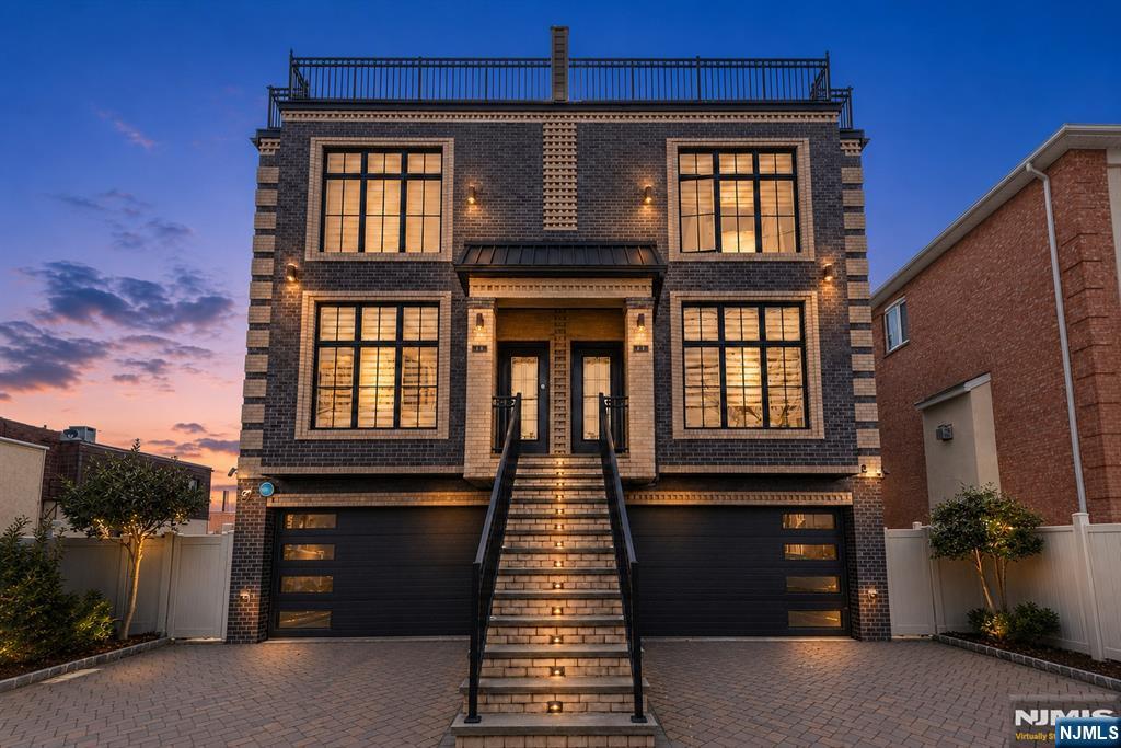 Welcome to this custom-built brick townhouse offering approximately 3,000 square feet of luxurious living across four levels. This modern home features 3 bedrooms, 3 full baths, and 2 half baths, thoughtfully designed for both everyday living and entertaining. The ground floor offers a separate entrance leading to a spacious studio layout with a gas fireplace, full bath, wet bar, separate A/C, and sliders opening to the fenced backyard patio. The first floor makes a grand impression with an open-concept living room featuring a gas fireplace, flowing into a gourmet eat-in kitchen with stainless steel appliances, a center island, and sliders to the deck. A formal dining area, half bath, and custom wainscoting and crown molding complete this level. The second floor is home to a grand primary suite with a spa-like bath featuring a custom double vanity and shower, plus two additional generously sized bedrooms with high ceilings and a full bath. The third floor offers a versatile kitchenette, half bath, and a private rooftop deck with sweeping NYC skyline views, perfect for entertaining or relaxing. Additional highlights include custom blinds, exterior lighting, an exterior security camera system, the high-end Lyric smart alarm system (remotely manage lights, locks, and water supply), Sonos-ready interior/exterior speakers, and central vacuum. A rare blend of space, style, and smart-home convenience. This is modern townhouse living at its finest.