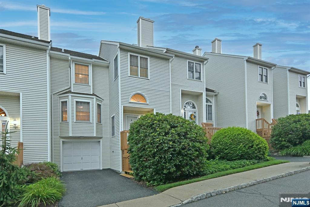 Welcome to Skyline Village! This meticulously maintained townhouse features two bedrooms and two and a half bathrooms, complemented by a finished basement and an attached one-car garage. Upon entering, you are welcomed by an elegant tiled foyer, which includes a spacious coat closet. The first floor showcases an updated half bath and a large eat-in kitchen with a breakfast area, equipped with granite countertops and stainless steel appliances. The dining room, adorned with hardwood flooring, offers sliding doors that lead to a private deck, surrounded by tranquil scenery. The living room impresses with soaring cathedral ceilings, a wall of windows, skylights, and a cozy wood burning fireplace. On the second level, you will find the primary bedroom, featuring a walk-in closet, an additional closet, skylights, and an updated full bath. The second bedroom is bright and inviting, with access to another updated full bath. The full, finished basement includes a laundry area, ample storage space, and a designated office/gym area, along with access to the oversized one-car garage. The community amenities include a heated pool and clubhouse, all within minutes of downtown and conveniently located near major highways and the NJ Transit Bus and Train Center.