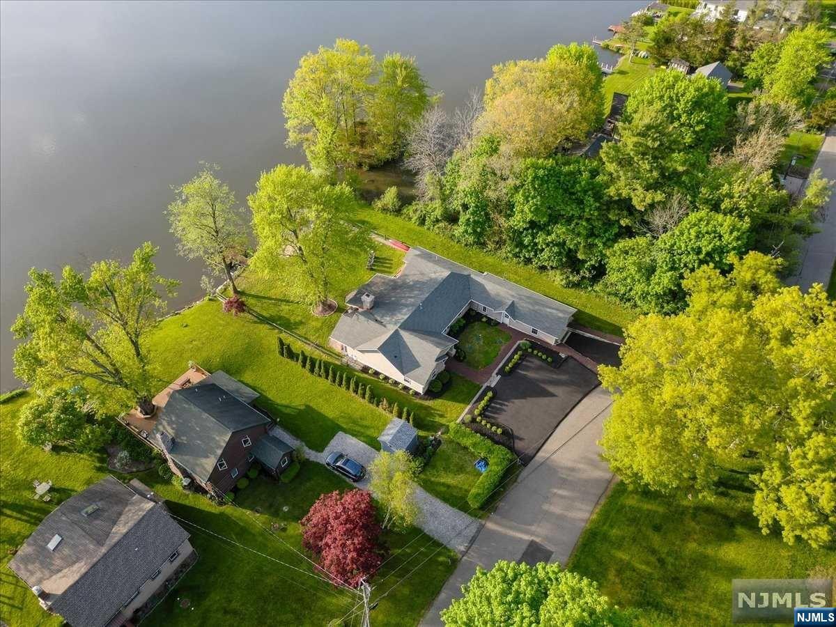 This lakefront ranch, renovated in 2015, offers a tranquil escape with stunning views of the lake and mountains. It features 4 bedrooms, 2 baths, and 90 feet of lake frontage with a private dock. The backyard includes a fire pit and a private 20x20 island for picnics. The patio pavilion, with a fireplace, is perfect for outdoor dining. Inside, there's an open floor plan with a designer kitchen boasting Kitchen-Aid appliances, granite countertops, and a wine fridge. The home also has elegant touches like crown molding and stylish bathrooms. The master bedroom has a cathedral ceiling and French doors opening to a covered patio with lake views. It's a unique opportunity to own this serene retreat with its own private island.