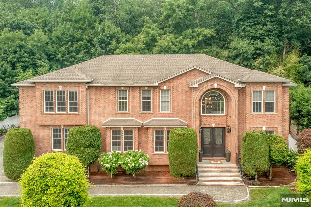 A rare offering on Demarest's coveted East Hill, this exceptional all-brick Colonial blends timeless architecture with sophisticated modern living. A dramatic two-story foyer with a sweeping staircase opens to elegant entertaining spaces and a spectacular two-story great room with fireplace. The gourmet chef's kitchen is appointed with premium Wolf appliances, custom cabinetry, and a generous center island, seamlessly connecting to the heart of the home. Expansive glass sliders lead to a paver patio and private fenced backyard backing to a nature preserve, offering tranquil views and exceptional privacy. The main level also features a guest bedroom with full bath, mudroom with custom storage, powder room, and access to the 3-car garage. Upstairs, the luxurious primary suite offers a fireplace, two walk-in closets, and a spa-inspired bath with radiant heated floors. An additional en-suite bedroom, two spacious bedrooms, hall bath, laundry room with utility sink, and balcony overlooking the backyard complete the second level. The finished lower level offers a bright recreation room with high ceilings, full bath, and a private bonus room with closet, perfect for extended-stay guests, a home office, fitness studio, or media room. Additional highlights include hardwood floors, central vacuum, alarm/security system, underground sprinklers, paver driveway, and proximity to top-rated schools, parks, shopping, dining, and NYC transportation.