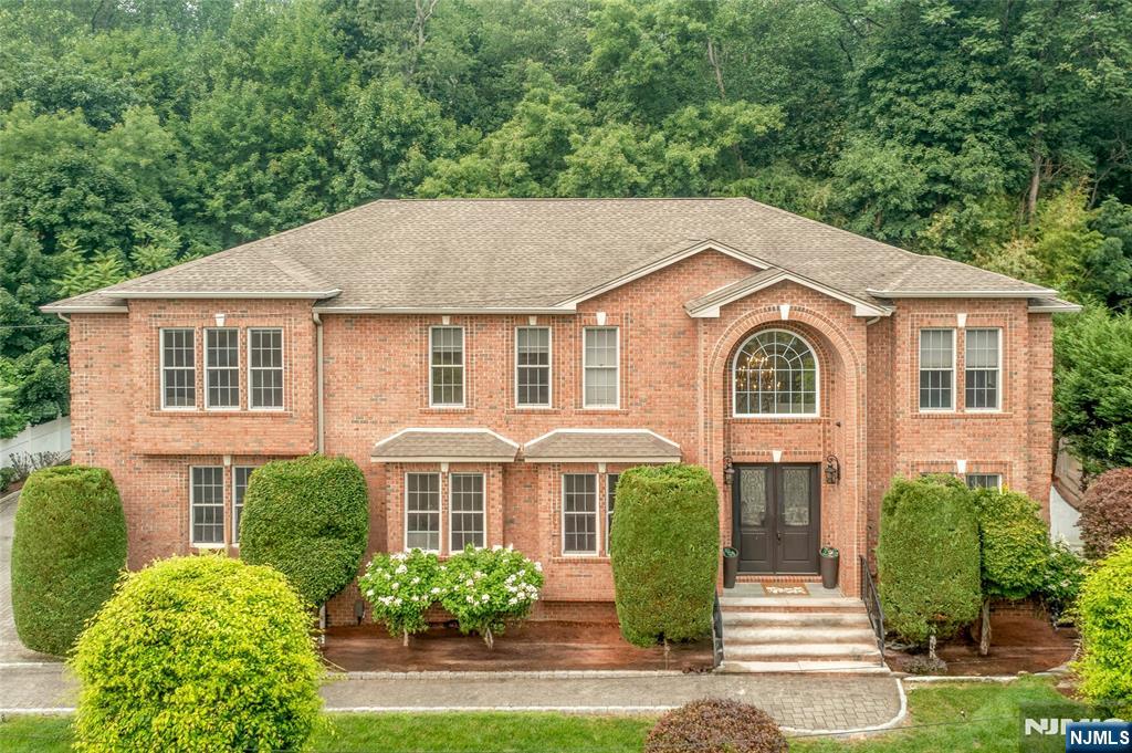 A rare offering on Demarest's coveted East Hill, this exceptional all-brick Colonial blends timeless architecture with sophisticated modern living. A dramatic two-story foyer with a sweeping staircase opens to elegant entertaining spaces and a spectacular two-story great room with fireplace. The gourmet chef's kitchen is appointed with premium Wolf appliances, custom cabinetry, and a generous center island, seamlessly connecting to the heart of the home. Expansive glass sliders lead to a paver patio and private fenced backyard backing to a nature preserve, offering tranquil views and exceptional privacy. The main level also features a guest bedroom with full bath, mudroom with custom storage, powder room, and access to the 3-car garage. Upstairs, the luxurious primary suite offers a fireplace, two walk-in closets, and a spa-inspired bath with radiant heated floors. An additional en-suite bedroom, two spacious bedrooms, hall bath, laundry room with utility sink, and balcony overlooking the backyard complete the second level. The finished lower level offers a bright recreation room with high ceilings, full bath, and a private bonus room with closet, perfect for extended-stay guests, a home office, fitness studio, or media room. Additional highlights include hardwood floors, central vacuum, alarm/security system, underground sprinklers, paver driveway, and proximity to top-rated schools, parks, shopping, dining, and NYC transportation.