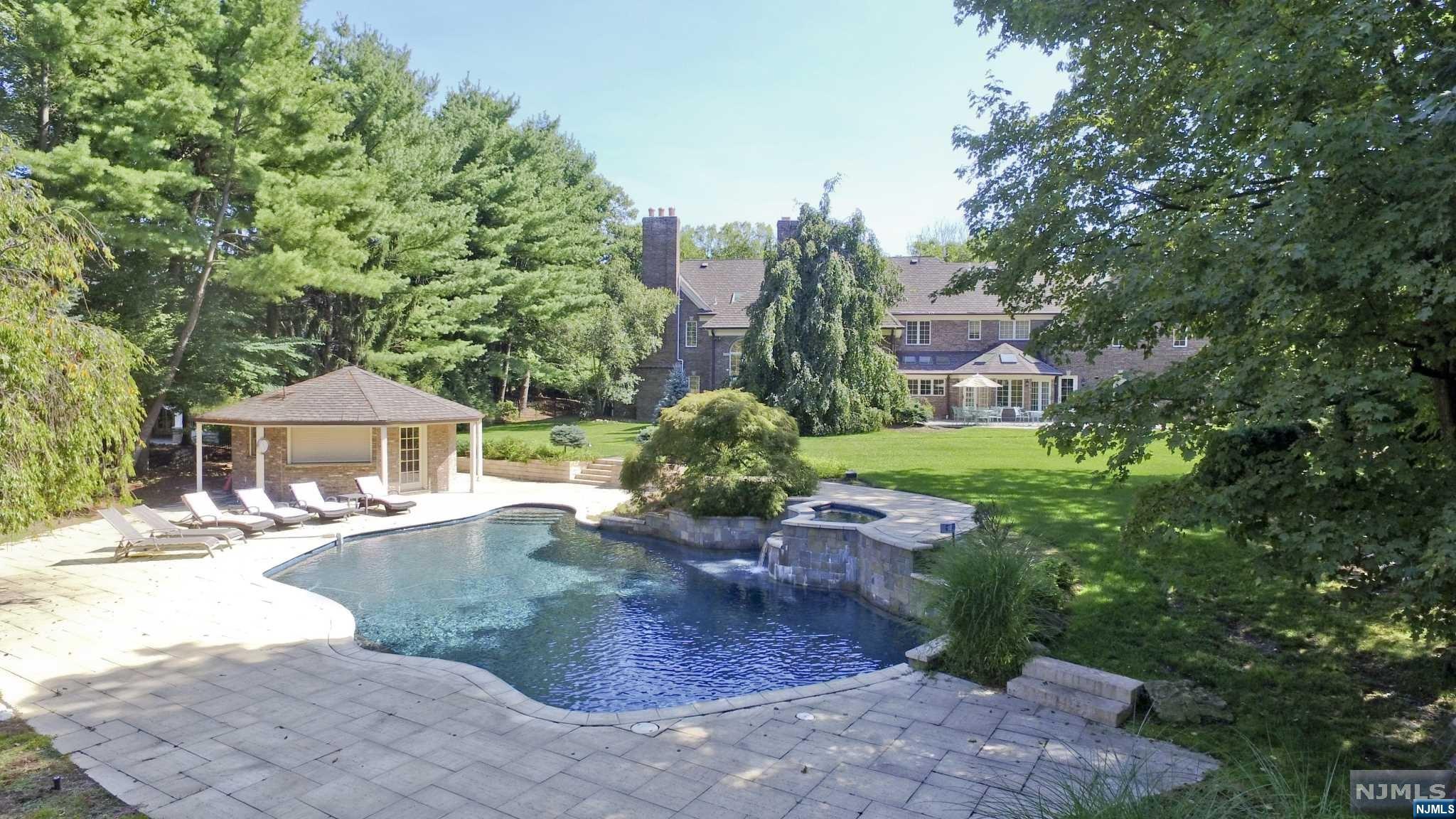 One of the most beautiful settings in all of Franklin Lakes, this oversized property is backed by a nature preserve offering complete privacy. The 11,000+sf. brick manor offers an open floor plan. The 2-story entry hall has a double bridal staircase and opens to both a banquet dining room and formal living room with a music alcove. The 2-story great room with fireplace and bar area is ideal for large scale entertaining. The woodworked office/library includes a fpl and is well situated for working remotely. The very generously proportioned kitchen has a large island & breakfast area. There is a bedroom and bath on the 1st floor & the primary bedroom suite + 5 additional bedrooms on the 2nd floor. The finished lower level has a recreation area, theater area, gym/bth, kitchen area, office & powder room. There is an attached 4-car garage and a separate 2-car garage. The resort setting includes a pool with waterfalls & spa, cabana, and large patio areas.