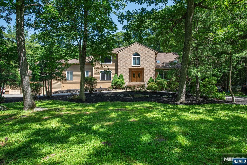 Rare opportunity to own an expansive estate in the prestigious gated Smoke Rise community, offering exceptional flexibility for multi-generational living or extended guests. The main level features a private guest wing w/ 2 bedrooms, walk-in closets, a full bath, LR with fireplace, and a kitchen with dinette, plus a separate guest suite with its own full bath and walk-in closet. The main living areas showcase soaring ceilings, a dramatic living room with a wet bar, and a spacious family room with a fireplace. All-new Anderson windows fill the home with abundant natural light. The kitchen offers a walk-in pantry, separate dining area, and excellent potential for your custom updates. A private home office w/ deck access and an adjacent full bath adds more versatility. Upstairs the primary suite features a sitting area, updated bath, oversized walk-in closet, and cedar closet. 3 additional bedrooms complete the second level. The lower level offers endless possibilities for recreation, fitness, or entertaining. Outside, enjoy a large rear deck with a built-in outdoor kitchen overlooking the level backyard. Additional highlights include a whole-house generator & oversized 4-car tandem garage. Enjoy 24-hour gated security and the Smoke Rise Club w/ Lake Kinnelon, swimming, boating, fishing, tennis, equestrian facilities, playgrounds, social events, and the Village Inn. A rare opportunity to create your dream home in one of northern New Jersey's premier private communities.