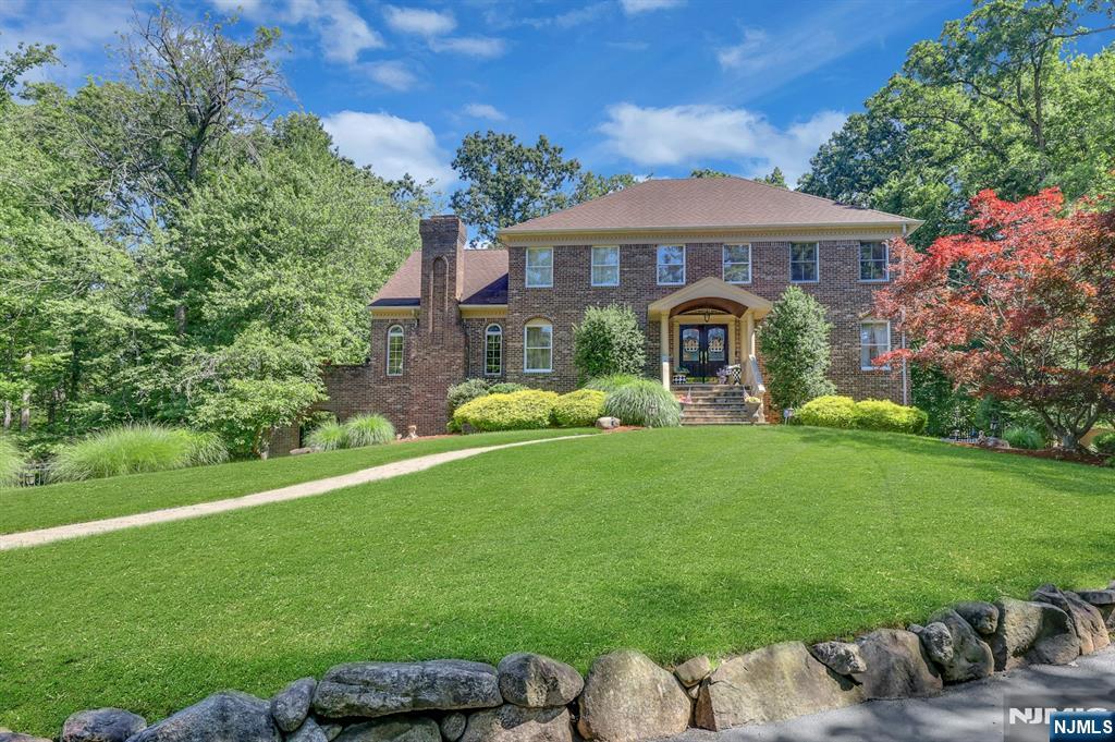 An Extraordinary Private Retreat! Beautifully situated on a picturesque 0.86-acre property overlooking a tranquil private pond, this exceptional 3,800 sq. ft. Center Hall Colonial (plus an approximately 700 sq. ft. walk-out lower level) offers nearly 4,500 sq. ft. of finished living space with 4 bedrooms and 3.5 baths. A gracious foyer welcomes you into elegant living spaces featuring hardwood floors, crown molding, custom millwork and abundant natural light. The spectacular Great Room showcases a vaulted ceiling, oversized windows framing peaceful pond views, a stone gas fireplace, custom built-in entertainment center and French doors opening to the formal living room. Sliding glass doors lead to the expansive maintenance-free wraparound deck overlooking the lush backyard, tranquil pond and breathtaking sunsets. The renovated Ulrich custom kitchen (2020) features rich maple cabinetry, granite countertops, premium stainless steel appliances, center island and sunny breakfast area. Formal dining room, first-floor office, powder room and laundry complete the main level. The primary suite offers a walk-in closet with custom built-ins and spa bath with Jacuzzi tub, double vanities and skylight. Finished walk-out lower level with recreation room, full bath, sliders to covered patio and abundant storage. Additional features include 6-zone heat, 2-zone central air, tankless hot water, underground sprinklers, oversized garage, well, septic and Northern Highlands Regional High School.