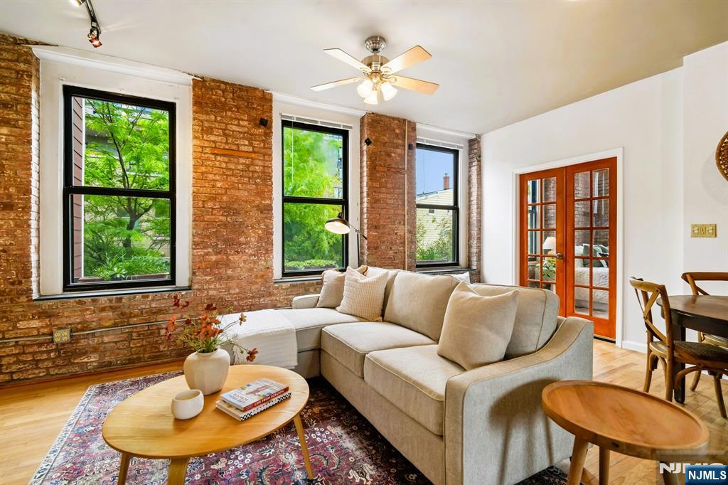 Discover authentic loft living at the iconic Chocolate Factory Lofts in Newark's vibrant Ironbound district, just two blocks from Newark Penn Station with direct access to NYC. This distinctive residence blends historic character with modern comfort, featuring soaring ceilings, exposed brick walls, heavy timber columns, oversized windows, central air conditioning, and an open-concept layout filled with natural light. Thoughtful architectural details throughout include antique raised panel doors, pocket doors, salvaged wood kitchen shelves, custom handmade tile, granite counters, and hardwood flooring that complement the loft's industrial character. Enjoy peaceful garden views and exceptional cross ventilation from North, East, and South exposures, a rare feature that enhances both light and airflow throughout the home. The spacious living and dining areas create an ideal setting for entertaining, relaxing, or working from home. The loft offers two sizable bedrooms and a rare garage parking space for added convenience. Located in one of Newark's most dynamic neighborhoods, enjoy easy access to restaurants, cafes, shopping, NJ Transit, PATH trains, Newark Liberty International Airport, Prudential Center, and all that Downtown Newark has to offer.