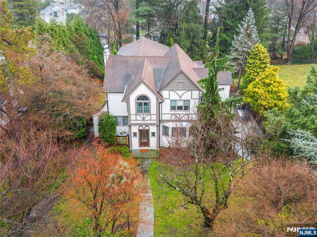 Experience the perfect blend of suburban tranquility and urban accessibility in this contemporary Tudor-style residence located on one of the most desirable streets in Ridgewood's Old Country Club section. Situated on 0.4 acres, this 5-bedroom, 6-bath home showcases a meticulously maintained interior with adaptable living areas. The inviting foyer leads to a living room featuring a fireplace, flowing into a formal dining room and spacious eat-in kitchen, which opens onto an oversized bluestone patio perfect for outdoor dining. Convenient 1st floor ensuite bedroom, 2-story ground level great room lined with glass doors to another outdoor living area, and laundry complete the 1st level. Upstairs offers a vaulted ceiling primary bedroom ensuite, ensuite bedroom, and 2 bedrooms with a hallway bath. The finished basement provides a rec room, office, full bath, gym, and access to a 3-car attached garage. Enjoy all this just minutes from top schools, vibrant downtown, and NYC transportation!
