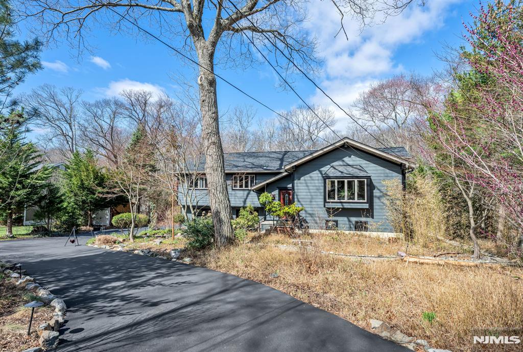 Spectacular, one-of-a-kind home with an upscale flair far from typical! This unique property features an elevated living room w/vaulted ceiling, filled with natural light and designed for open, airy living. A few steps up, the formal dining room impresses with high ceilings and sliding glass doors leading to a deck overlooking a serene backyard perfect for indoor-outdoor entertaining. The exceptional kitchen is anything but ordinary, Showcasing a large center island w/ honed travertine & seats 4, endless cabinetry, granite countertops, & an oversized 6-burner stove with griddle & hood vent - a dream for everyday living, gourmet cooking & entertaining. A large bay window allows for beautiful natural views while you cook & gather. This level offers three spacious bedrooms and an updated full bath. The lower level adds even more living space with an industrial-style family room featuring a waxed cement floor, open beamed ceiling, and a wood-burning brick fireplace, 4th bedroom / office w/full bath & walkout to patio, large media / bonus room, powder room & laundry complete the space, plus Sliding glass doors leading to a large composite deck ideal for hosting or relaxing. 2 car garage. Additional highlights include a circular driveway with plenty of parking, maintenance-free landscaped front yard means no lawn mower needed, Hardy plank siding, newer Andersen windows, new C/A Private rear yard. prime location close to shopping, restaurants, parks, & NYC Express bus