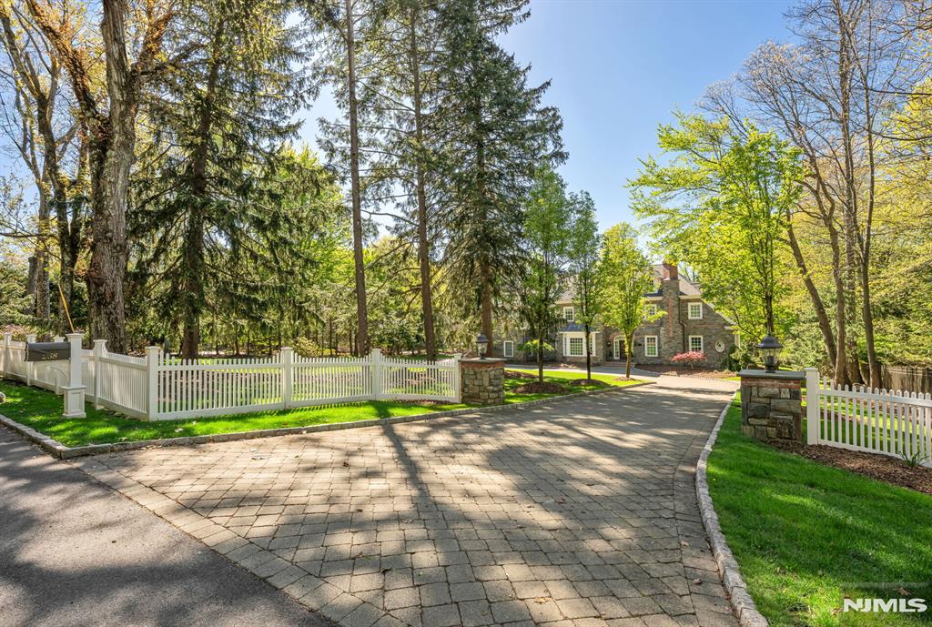 Nestled behind a private approach on 1.6 meticulously landscaped acres in coveted Franklin Lakes, this magnificent stone manor evokes the feeling of the English countryside while delivering every modern luxury imaginable. The grounds are nothing short of extraordinary. Mature trees and sweeping lawns create an idyllic sanctuary. Inside, the layout unfolds with thoughtful precision, offering over 10,000 sf of living space across three levels. Sun drenched principal rooms flow seamlessly, each graciously scaled for both grand entertaining and intimate living. The chef's kitchen anchors the heart of the home, while a custom library positioned to capture sweeping views over the grounds speaks to a residence designed with intention at every turn. Upstairs, the luxe primary suite is a true retreat, complete with a sitting room, fireplace, spa like bath, steam shower and dual walk in closets. Four addt'l ensuite bedrooms and a laundry room complete the level. The LL rivals any private club. A French Laundry inspired, temperature controlled wine cellar sits alongside a custom hand crafted bar, entertainment lounge, theater, gym, full bath w/steam shower, an entertainer's dream executed to perfection. Systems throughout are of the highest caliber: Crestron home automation, hydro coil and radiant heat, 6 zone cooling, generator, and a 3 car attached garage round out this exceptional offering. Rarely does a property of this caliber come to market. Franklin Lakes at its absolute finest.