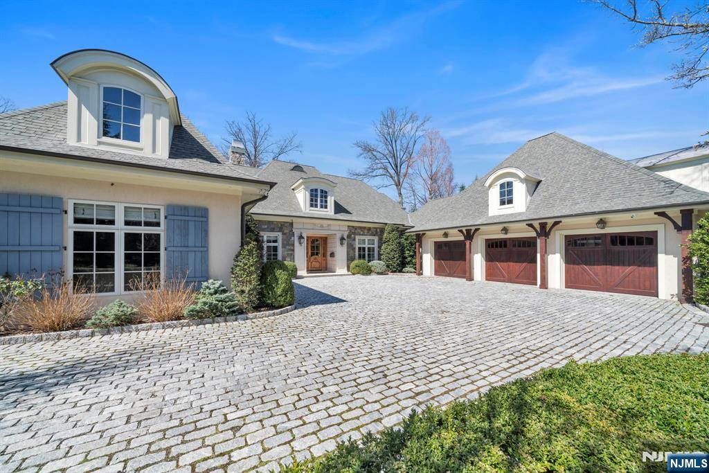 This custom French countryside home was designed by renowned architect Jordan Rosenberg and built by distinguished firm Rock Ridge Construction, with timeless craftsmanship and attention to detail throughout. Privately surrounded by mature landscaping, it features coffered ceilings, herringbone-patterned floors, and intricate millwork. The kitchen blends style and function with a dramatic stone island, Wolf appliances, and custom cabinetry. A beautifully crafted wood-paneled elevator serves all three levels, including a lower level with a tiered theater, temperature-controlled wine room, and spacious multi-use room. The primary suite offers a fireplace, spa bath, boutique dressing room, and built-in bar. A three-car garage with soaring ceilings accommodates lift potential. Bluestone patios, whole-house generator, and thoughtfully curated finishes complete this exceptional offering in one of Englewood Cliffsâ€™ most sought-after locations.