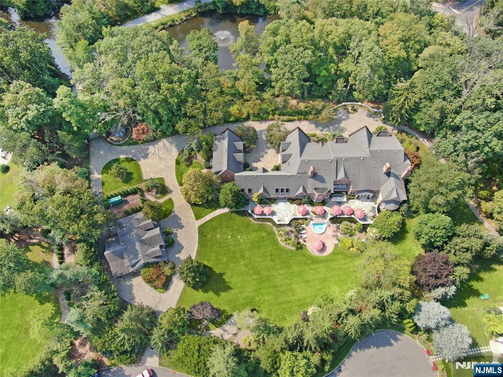 Private resort-style estate set on 6.5 gated acres. Surrounded by lush landscaping, a tranquil private lake, and a picturesque bridge approach, this extraordinary 9-bedroom residence offers over 18,000 sq. ft. of refined living space with exceptional architectural detail, timeless millwork, and elegant interiors with a warm and inviting feel throughout. Designed for luxury living and entertaining, the estate features a private wellness retreat with indoor pool, professionally lit tennis court, climate-controlled 6-car garage, private apartment within the main residence, and a separate carriage house ideal for extended living or a sophisticated home office. A one-of-a-kind estate combining privacy, serenity, and the feeling of a truly private retreat while still providing close, convenient access to Manhattan.