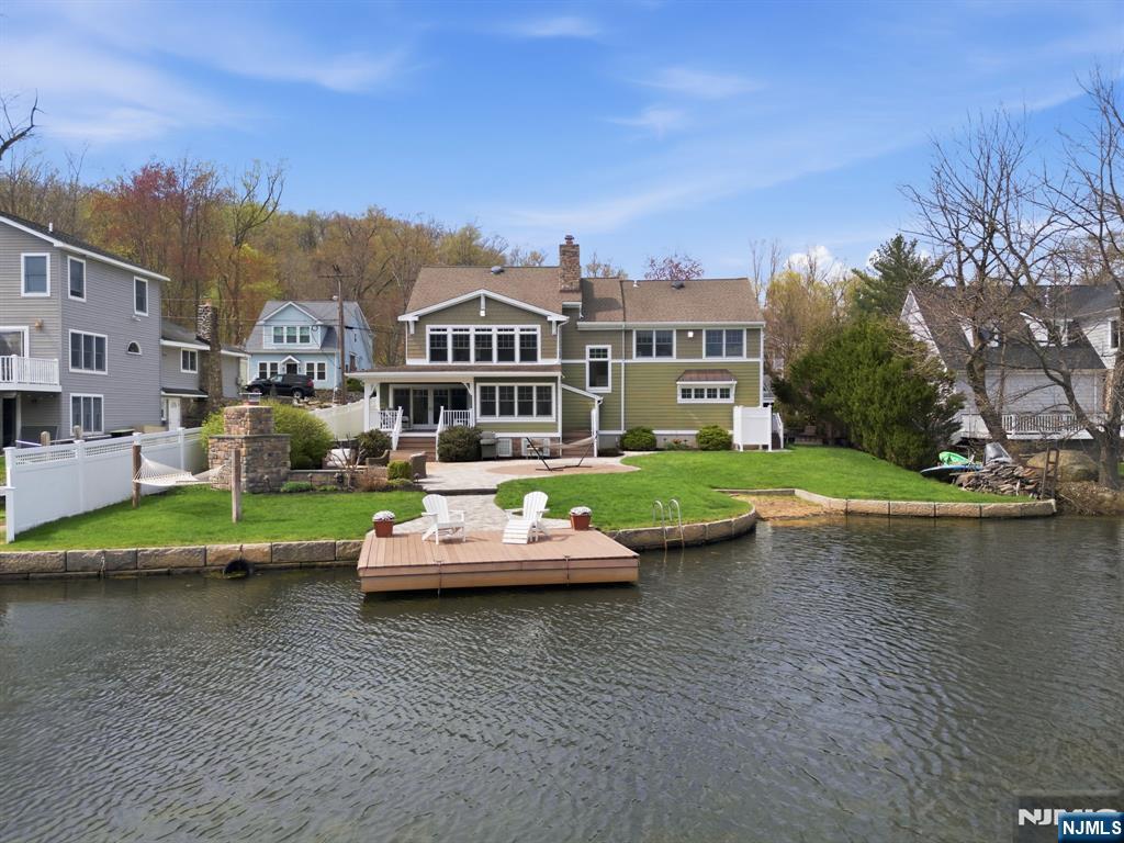 Absolutely stunning lakefront Craftsman style Colonial on one of the most desirable & few double lots on Indian Lake, offering panoramic water views & timeless design. 6 BDRM / 3.5 BATH TOTAL. Open concept main level with hand scraped HW floors, a striking stone fireplace & a sunroom with cedar plank-style ceiling extending the living space with full lake views. Classic kitchen with granite, shaker cabinetry, SS appliances & walk-in pantry. Dining room with double sliders seamlessly connects to the outdoors, perfect for Summer entertaining. Incredible family room currently set as a pub style room with coffered wood ceilings, stone wall facade, raised booth seating & full wet bar. Upstairs features 5 bdrms & 2 full baths, including a primary suite with high ceilings & 2 walk in closets. The walk up attic offers expansion potential. Smart recent updates include french drains & natural gas generator which adds peace of mind. Resort style exterior with private beach, dock, patio, fireplace, hot tub, outdoor shower & lawn for games & relaxation. Fenced in for privacy. Bonus 1BR/1BA apartment over 2 car garage with private entrance, parking & meters ideal for guests or rental income. Enjoy everything the ILCC community has to offer, including a clubhouse, 3 beaches & motorboat friendly waters. With year round activities for all ages, from boating, swimming & fishing to ice skating, this is more than a home, it's a lifestyle. Minutes to DWTN Denville, NYC transit & major highways.