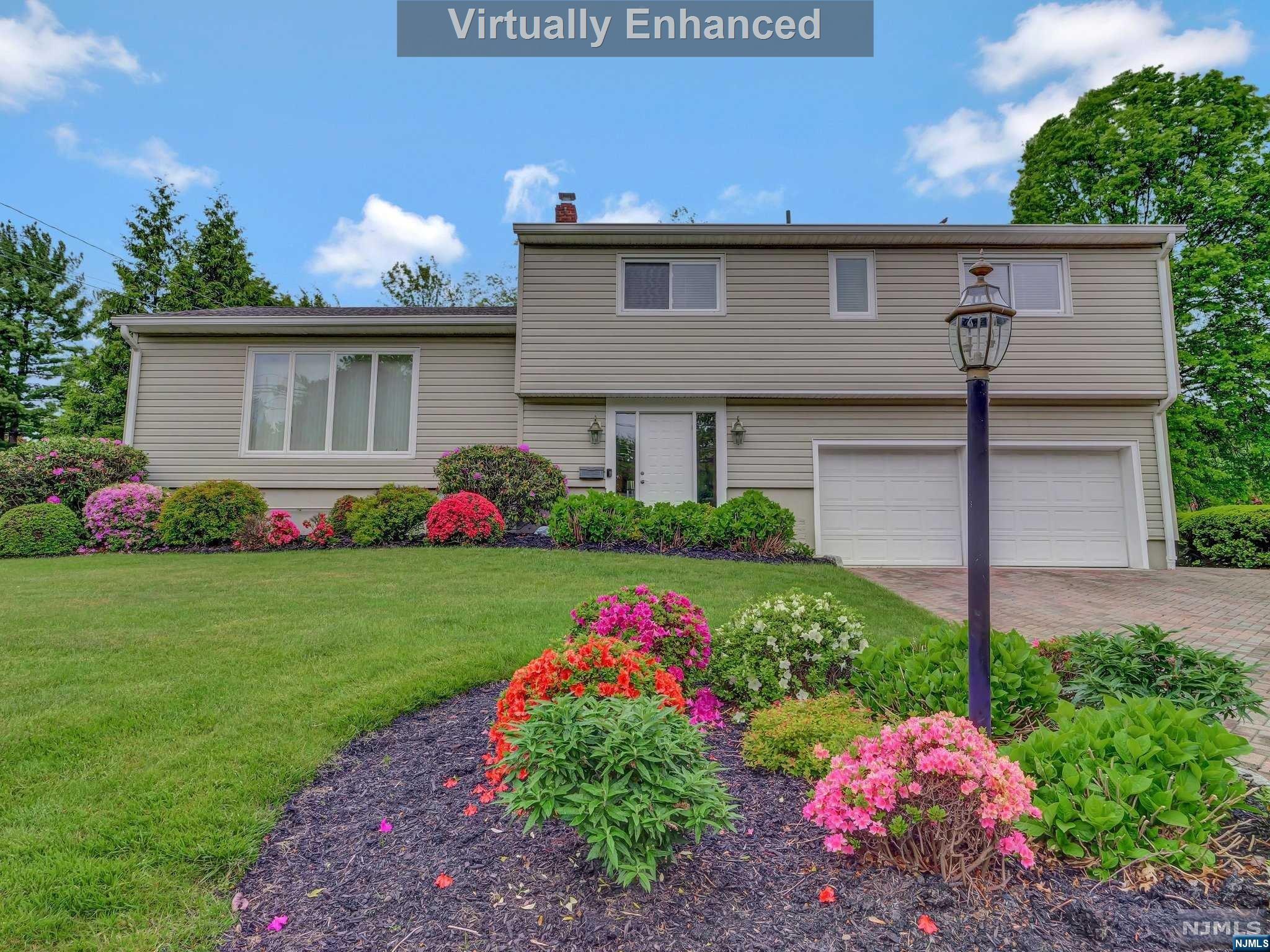 Beautifully maintained 4-bedroom, 2.5-bath home on a desirable street with a well-manicured lot. The entry foyer leads to a spacious family room with glass sliders to a large paver patio, perfect for entertaining under a large awning. The ground floor features a home office/5th bedroom, rec room, laundry room, and garage entrance. Upstairs, the living room flows into a bright dining room. The kitchen boasts custom cabinetry, granite countertops, black stainless appliances, and an island with bar seating. The primary bedroom includes a large closet and en suite with a glass-enclosed shower. Three more bedrooms and a full bath complete the second floor. The partially finished basement offers a second office and exercise room. Large, flat rear yard and ample driveway parking. Convenient to NYC transportation, shopping, and dining.