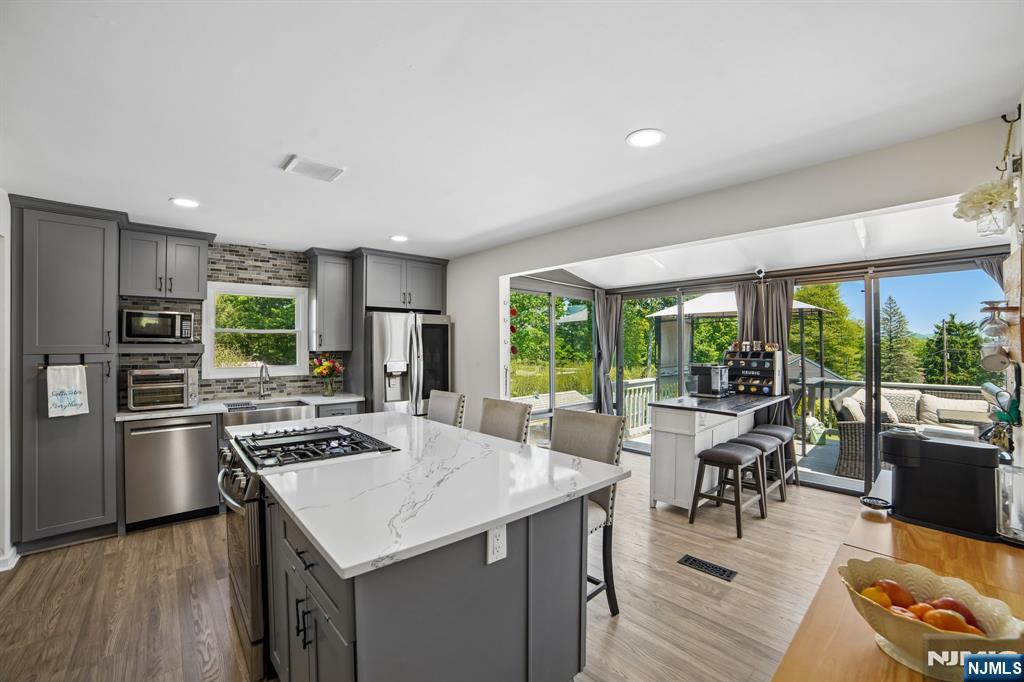 Beautiful 4-bedroom, 2 full bath home situated on an oversized corner lot in the highly desirable Birch Hill Estates section of West Milford. This well-maintained property offers an ideal blend of comfort, functionality, and thoughtful updates throughout. Step inside to find a beautifully expanded and renovated kitchen designed to be the heart of the home with ample cabinetry, generous counter space, and an open layout perfect for everyday living and entertaining. Updated bathrooms, new flooring, and all new Anderson windows throughout further enhance the home's appeal. The property's gentle slope creates the benefit of a desirable walk-out lower level while showcasing views of the expansive yard and outdoor space. The oversized corner lot provides plenty of room to relax and entertain. A bright three-season room extends your living space and opens directly onto the deck through three sliding glass doors, creating a seamless indoor/outdoor flow. Unwind in the hot tub while enjoying the peaceful backyard setting. One of the few homes in the neighborhood offering both municipal sewer and public water service. Conveniently located near parks, schools, shopping, dining, and commuter routes, this home delivers the perfect combination of location, updates, and convenience. Showings start Sunday, 5/24/2026