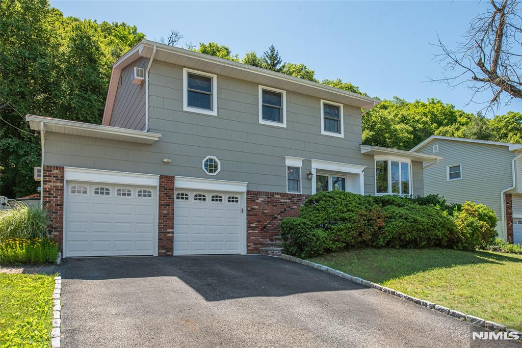 Welcome to 44 Molinari Drive, a beautifully maintained four bedroom, two and half bathroom, split-level Colonial offering comfort, style, and a functional floor plan in a sought-after Wanaque neighborhood with amazing mountain views. Warm hardwood floors flow throughout the home, creating an inviting atmosphere. The newly updated eat-in-kitchen features stainless steel appliances, ample dark wood cabinetry, and plenty of space for everyday living and entertaining. The spacious primary suite provides a private retreat, while the walkout lower level offers added flexibility for a family room, home office, recreation space, or guest accommodations. Step outside to a fenced backyard with a patio, perfect for outdoor dining, relaxing, and enjoying the changing seasons. Additional highlights include an attached 2-car garage, mature landscaping, newer windows, newer hot water heater and a convenient location close to schools, parks, and transportation. Move-in ready and meticulously cared for, this home combines timeless appeal with modern updates.