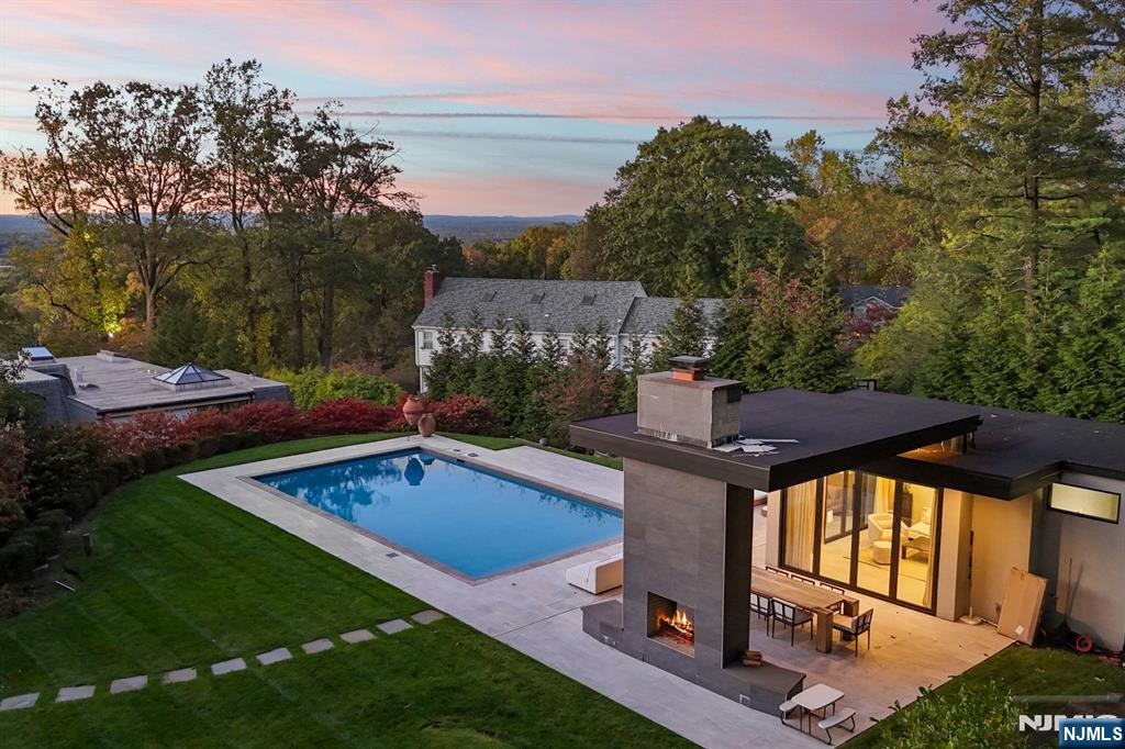 Escape to this private estate surrounded by nature and refined luxury. Set high on nearly an acre of exquisitely landscaped grounds bordering the Tenafly Nature Center, this residence offers unmatched privacy and scenic beauty. A true sanctuary, it features cascading waterfalls, a koi pond, lush gardens, and multiple stone terraces for relaxation and entertaining. At its heart, a new pool house with wet bar and bath overlooks the sparkling pool, outdoor fireplace, and expansive sitting areasâ€”creating a resort-caliber experience rarely found in Tenafly. Inside, timeless craftsmanship defines light-filled spaces including a gracious living room with fireplace, formal dining room, inviting family room, and gourmet kosher kitchen with custom cabinetry and professional appliances. The serene primary suite with spa bath is joined by five bedrooms, three full baths, a home theater, gym, and wine cellar. With slate roof, four-car garage, generator, and premier location, this estate epitomizes elegant modern living.