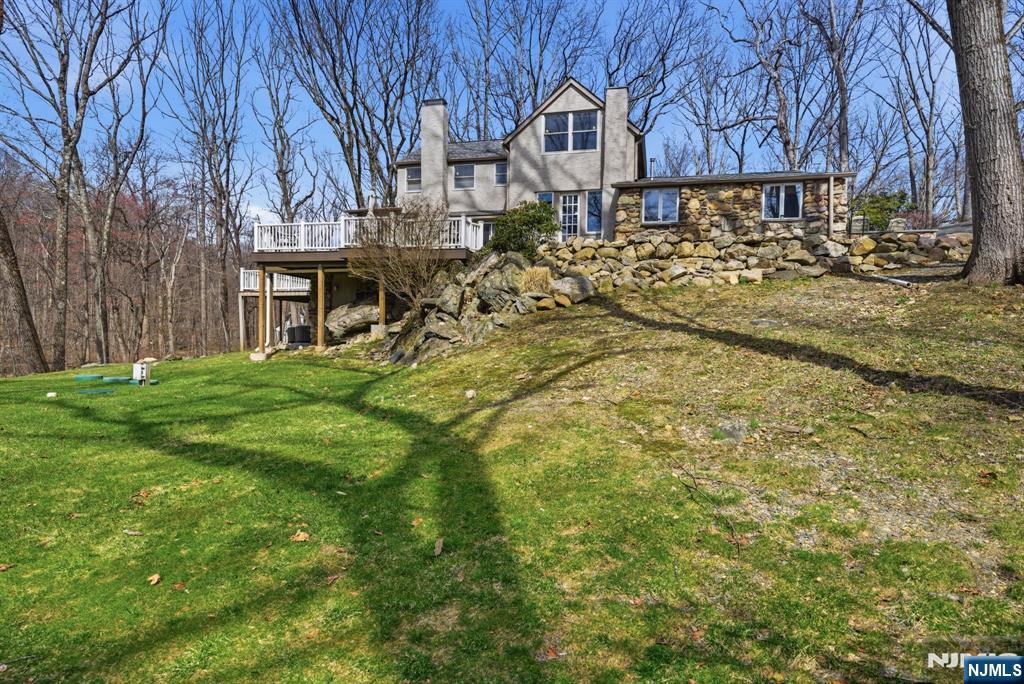Nestled in the highly sought-after Lake Valhalla section of Montville, this one-of-a-kind Habberstad custom colonial blends timeless charm, rich history & exceptional privacy on 3.3 wooded acres backing to 44 acres of preserved open space. Offering 4 bedrooms & 2.5 baths, this expansive home is filled with character beamed ceilings, custom woodwork, built-ins, a stunning wood-burning fireplace & hardwood floors throughout. The main level features formal living & dining rooms plus a spacious family room ideal for entertaining & everyday living. A 1st-floor primary suite with full bath & sitting area offers flexibility, while a den/home office adds versatility. The eat-in kitchen showcases shaker cabinetry, butcher block-style counters & classic black & white checkerboard flooring. Powder room & laundry complete the level. Upstairs offers 3 generously sized bedrooms, a sitting area & full bath. Enjoy multiple decks, including a new deck (2024), bluestone walkways, patio & mountain views surrounded by mature trees. Additional highlights: new roofs (2024 & 2026), new driveway (2025), new heat pump water heater (2024), dishwasher (2024), gas dryer (2023), fenced yard (2023), interior paint & blinds (2023). Circular driveway, garage, basement storage & shed. Minutes to Boonton Main Street, dining & commuter routes. Top-rated schools. A rare blend of privacy, updates & character. Northeastern facing front.