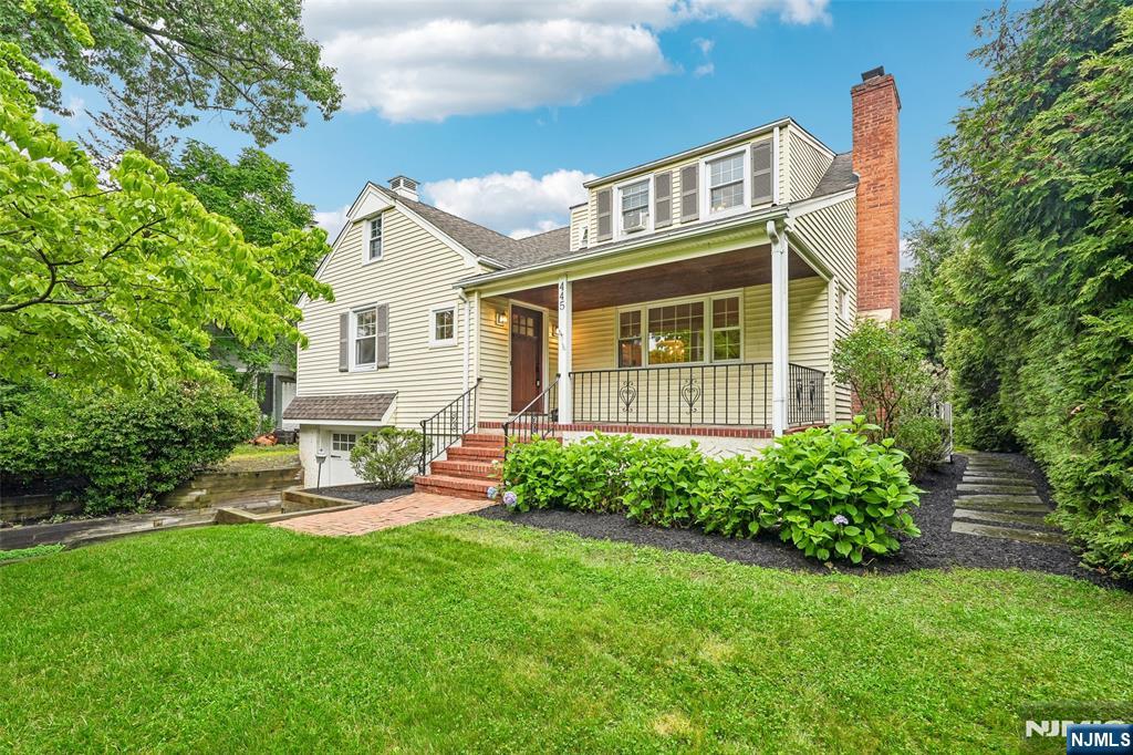 Welcome to this charming and beautifully maintained Colonial Cape nestled in Ridgewood's highly desirable Willard School neighborhood. A covered front porch creates a warm first impression and opens to inviting living spaces filled with natural light and hardwood floors. From the spacious living room with a fireplace, the home flows seamlessly into a dining area featuring sliding glass doors that open to the backyard, creating an effortless connection between indoor and outdoor living. The thoughtfully designed kitchen offers peninsula seating and abundant cabinet space. Flexible living arrangements include 2 first-floor bedrooms and a full bath, while the second level offers 2 bedrooms that share a full bath. Additional space awaits in the finished lower level, complete with a recreation room, laundry area, ample storage, and direct access to the attached tandem two-car garage. Outside, mature landscaping surrounds a private backyard complete with a paver patio and level lawn, perfect for entertaining, play, or quiet relaxation. Conveniently located within blocks of top-rated schools, parks, shopping, and NYC transportation, this move-in-ready home offers the ideal blend of comfort, character, and convenience!
