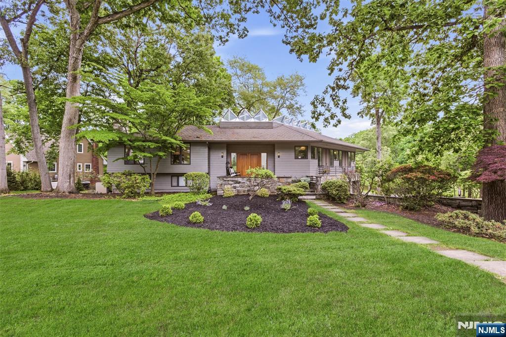 Distinctive 5-bedroom, 5 full bath, 2 half bath residence situated on over 1/2 acre in one of River Vale's most incredible neighborhoods. Offering over 5,000 sq ft of living space, this one-of-a-kind home is defined by its unique architectural design, flowing layout, oversized windows, and skylights that fill the home with natural light. The main level features a centrally located foyer, inviting living spaces, game room with a gas fireplace, powder room, and eat-in kitchen with double wall ovens, chef's refrigerator, walk-in pantry with a convenient dumbwaiter to/from the garage. The luxurious primary suite offers 2 walk-in closets, separate his-and-her full baths, dedicated office space, and a spacious bedroom area. Additional generously sized bedrooms provide ample closet space and access to nearby full baths. The lower level features a theater/family room with a wood-burning fireplace, projector, surround sound system, powder room, storage closets, and sliding glass doors leading to the backyard patio. Additional highlights include a gym/flex space with access to expansive wraparound deck, full bath with sauna, wine room, laundry and storage areas, multiple garage access points, and a substantial unfinished basement with high ceiling offering endless possibilities. With golf course views and close proximity to top-rated schools, parks, shopping, and dining, this is a rare opportunity to own one of River Vale's most architecturally distinctive homes.
