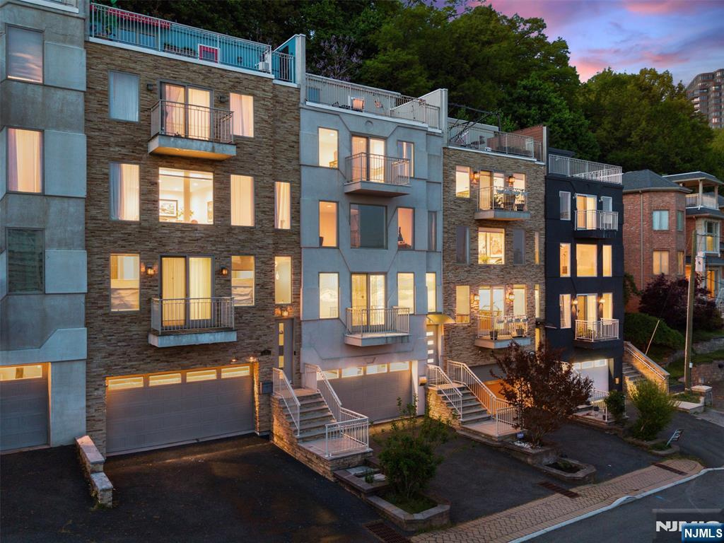 Will not last! 7 Oakdene Terrace is a rare 4,000 sq ft contemporary townhome with no HOA in desirable Edgewater, featuring a rooftop deck with panoramic Hudson River and Manhattan views, hardwood floors throughout, and an elevator shaft ready for future installation. Easy commute to Midtown NYC in under 30 minutes via bus or ferry, and walk to Whole Foods, Trader Joe's, Mitsuwa, parks, schools, restaurants, and SoJo Spa. This 4-bedroom, 3.5-bath home is designed for entertaining, highlighted by a spectacular 17' x 43' living room with an 18-foot double-height atrium, gas fireplace, family room, and a full bath added in 2021. The 22-foot eat-in kitchen features granite countertops, stainless steel appliances, and direct access to a private patio via sliding doors, overlooking the cliffs and backyard. The primary suite captures stunning river and skyline views and includes a private balcony, renovated spa-inspired bath (2021), and 2 walk-in closets. Two additional bedrooms, a full bath, and laundry complete the bedroom level. The rooftop level features a flexible sky room ideal as a lounge, office, or fourth bedroom, plus a deck showcasing breathtaking views. The finished lower level offers additional space for a gym, recreation room, or home office. Attached 2-car garage with EV charger. Recent upgrades include a new heating system (2020), Samsung washer/dryer (2020), renovated primary bath (2021), second-floor full bath (2021), and new AC units (2022)