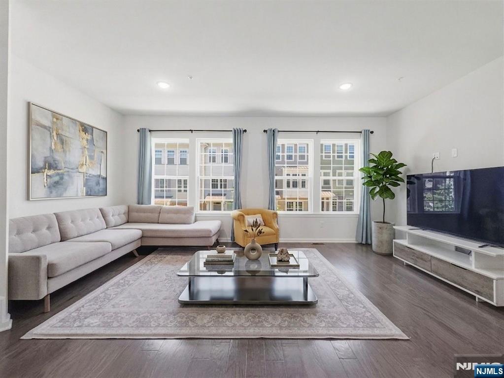 Call Mital Kataria at 732-789-0670 to schedule a tour. Welcome to this magnificent NORTH EAST facing 4 bedroom, 2.5 bath townhome that offers abundant natural sunlight, thoughtfully designed with premium upgrades throughout. Step into a sleek, modern interior featuring an open concept layout with serene views of a beautifully landscaped courtyard. The first floor offers a private bedroom perfect for guests, a home office, or multi-generational living. The main level showcases a spacious living and dining area along with a gourmet kitchen featuring custom built cabinetry, granite countertops, backsplash, SS Appliances, a large center island, farmhouse sink with garbage disposal, and an oversized pantry, with access to outdoor deck and upgraded hardwood flooring across most levels. Upstairs, retreat to the luxurious primary suite complete with dual custom built-in walk-in closets and a spa-inspired bath with a double vanity and standing shower, along with two additional bedrooms with custom shelving in closets and a full bath. Ideally located near NJ Transit train and bus lines for an easy NYC commute. Bonus features: a two-zone HVAC system with Smart Thermostats, reverse osmosis drinking water system, whole house water softener system and video doorbell, LiftMaster MyQ app enabled garage door and a two-car finished garage with electric car charger + driveway parking offering the perfect blend of modern luxury, comfort, and convenience.