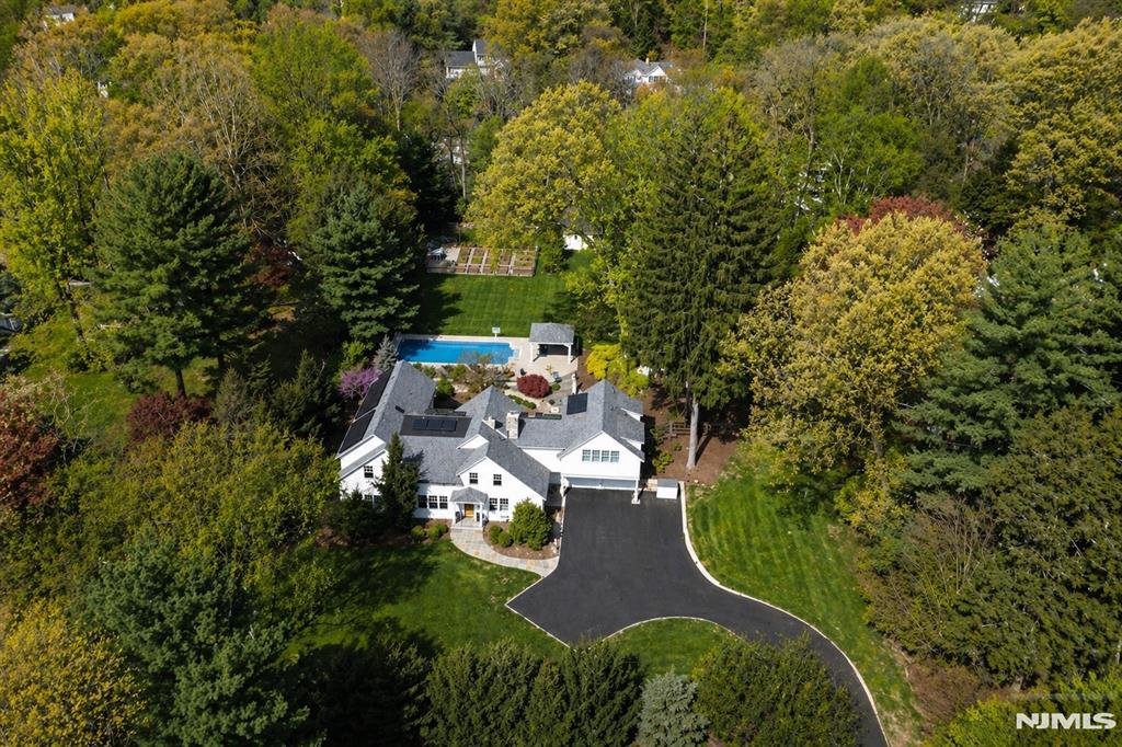 Originally built in 1826 and masterfully expanded and renovated, this exceptional Ramsey estate blends timeless character with sought-after amenities on 1.2 private, resort-like acres. The home showcases restored barn wood flooring, custom millwork and cozy fireplaces, while modern enhancements include a chef's kitchen, radiant heat, smart home technology, a whole-house generator and solar panels. Designed for both elegant living and effortless entertaining, the seamless layout flows from sophisticated interior spaces to an extraordinary outdoor retreat featuring a heated saltwater pool, hot tub, sport court and beautifully landscaped grounds with bluestone walkways, a pergola and mature privacy plantings. The home offers five spacious bedrooms including a luxurious primary suite, multiple living areas, a sun-filled office and a finished lower level complete with a home theater, gym, and sauna, creating a rare opportunity to own a one-of-a-kind residence that perfectly balances convenience with modern luxury. Ideally located in Ramsey, a highly sought-after Bergen County community known for its charming downtown, top-rated schools, vibrant dining scene and New York City commuter access, this home offers ultimate lifestyle.
