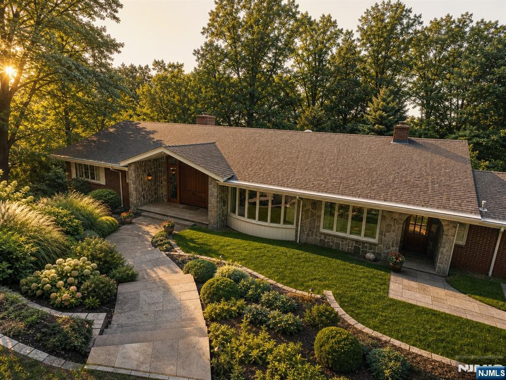 Beautifully updated ranch set atop a private 1.6-acre lot at the end of a quiet cul-de-sac, overlooking the Bergen County hills. This distinctive two-level home offers 4 bedrooms and 4 full plus 1 half baths, with custom architectural moldings and hardwood flooring throughout. The main level features a chef's kitchen with custom wood cabinetry and a double granite-slab island, while a second summer kitchen with natural stone floors serves the lower level. The primary suite includes a spa bath with steam shower and radiant-heat floors. Enjoy a red cedar sauna, whole-house water softener, and a bi-level covered porch. The grounds include a new outdoor pool, deck and pergola, lush natural landscaping, and ample room for a tennis court. Circular driveway and 2-car garage. Minutes from NYC in an award-winning school district.