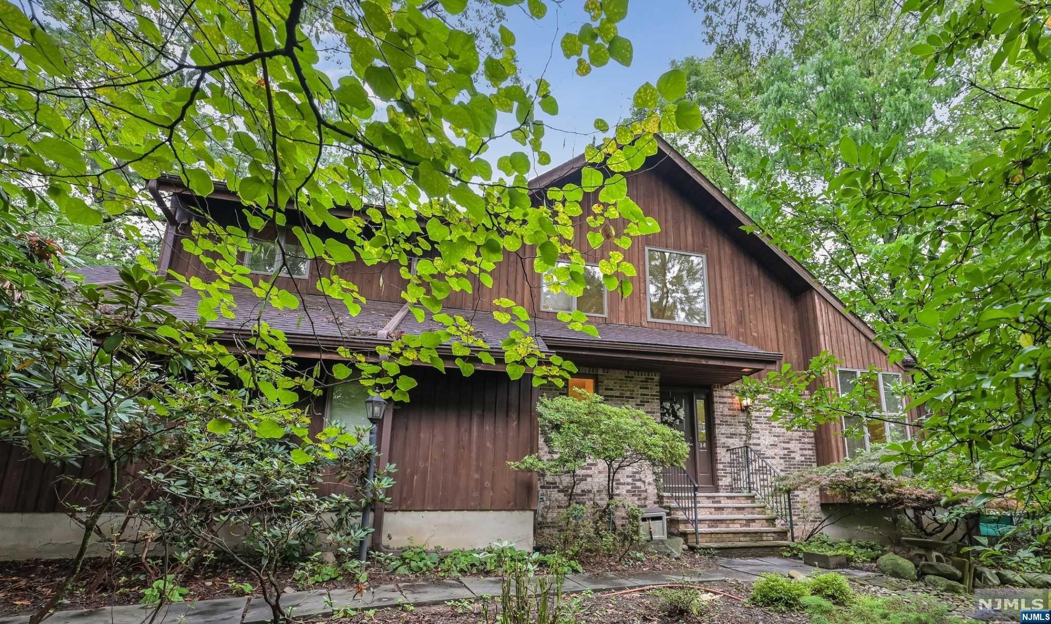 Welcome home! Wonderful contemporary colonial on private .30-acre wooded setting with open floor plan. 2-story entry foyer, vaulted living room, dining room with wet bar, center island kitchen with breakfast area open to family room with brick fireplace. Sliders off both family room & kitchen to the private rear deck. Powder room, laundry room and & 2 car garage complete the 1st Level. 2nd level offers large primary suite with fireplace, hardwood flooring walk-in closet & full bath. 3 additional bedrooms with hardwood and guest bath. The full unfinished basement with high ceiling is just waiting to be finished for additional living space. Property being sold in "as is " condition with no known issues. Call Leta or Colin for private showing at 201-446-3566