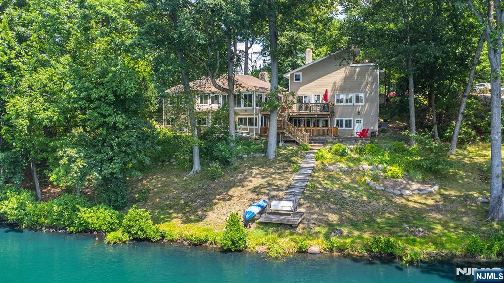 Don't miss this beautifully remodeled 5 bedroom 5 bath lake front home! This 4,000 square foot custom contemporary is set on nearly 1/2 an acre with property in both Denville and Mountain Lakes, and includes 150 feet of lake frontage. Ideally located on a quiet street just seconds from the town center and mass transit, this home combines a lake front retreat with the convenience and charm of downtown Denville. You'll enjoy gorgeous lake views from virtually every room in the home. From the spacious chefs kitchen with professional grade appliances, walk in pantry, and seemingly endless counter and cabinet space, to the Primary suite with it's own loft dressing room, this home checks every box. The living and dining rooms feature hardwood flooring, a vaulted ceiling, and share a wall of windows with stunning views & wood burning fireplace with a 2 story stone chase. The family room features its own storage space, a full bath, and access to the back yard patio area, and all bedrooms include oversize California-style closets. Additional features include a spacious deck overlooking the lake, a finished 2 car garage with storage and loft, multi zone heating and cooling, energy efficient windows, and more! The community offers access to 3 lakes for boating & fishing, a club house, beach access and activities, or you can fish and launch your boat from your own back yard!